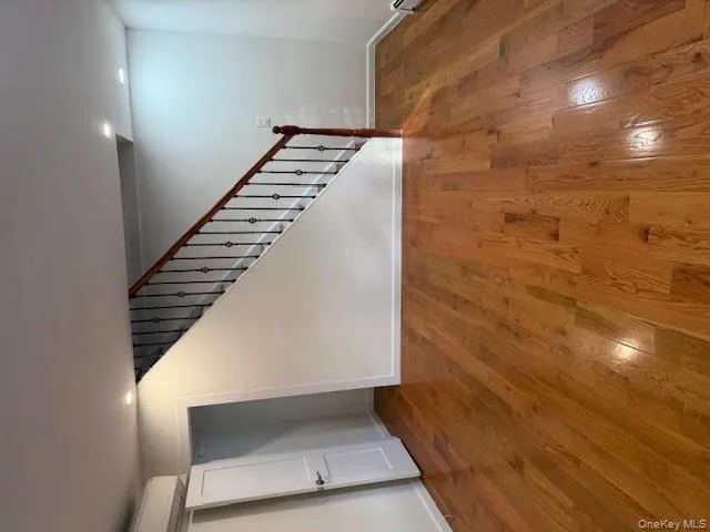 Unfurnished living room with stairway, wood-type flooring, recessed lighting, and a wall unit AC Unfurnished living room with stairway, wood-type flooring, recessed lighting, and a wall unit AC