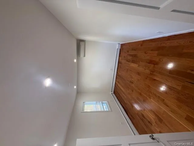 Empty room featuring dark wood-style floors, baseboard heating, recessed lighting, and an AC wall unit Empty room featuring dark wood-style floors, baseboard heating, recessed lighting, and an AC wall unit