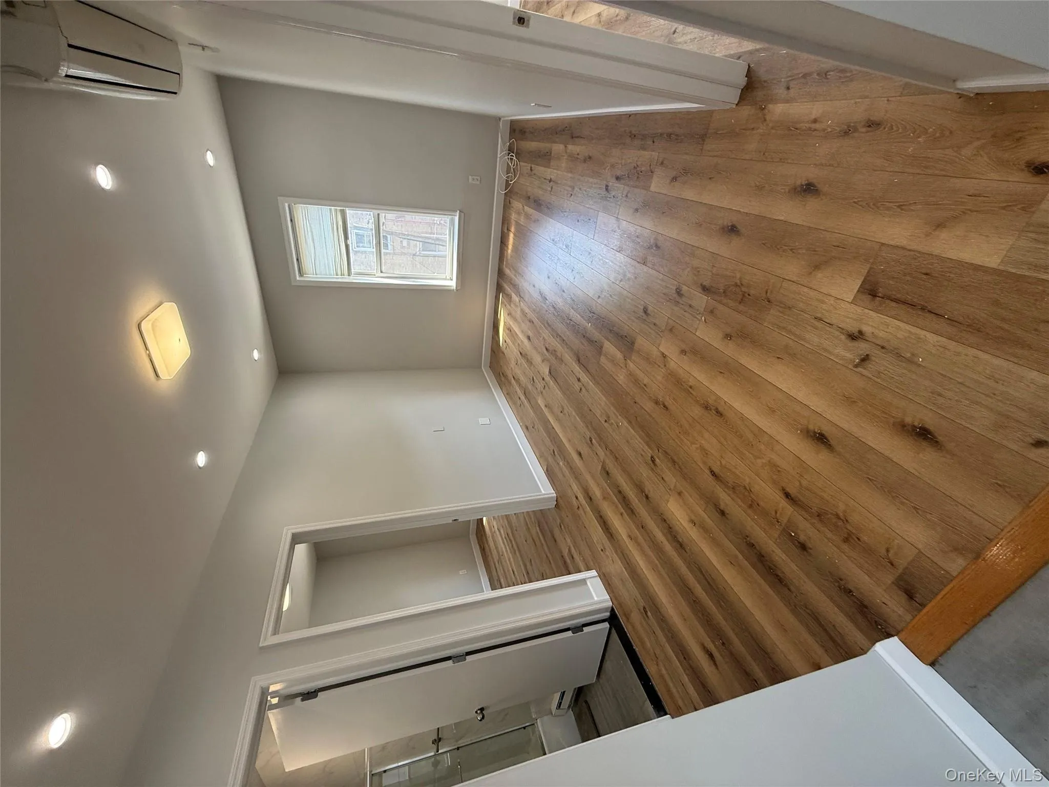 Unfurnished bedroom featuring an AC wall unit, wood-type flooring, recessed lighting, and ensuite bath Unfurnished bedroom featuring an AC wall unit, wood-type flooring, recessed lighting, and ensuite bath