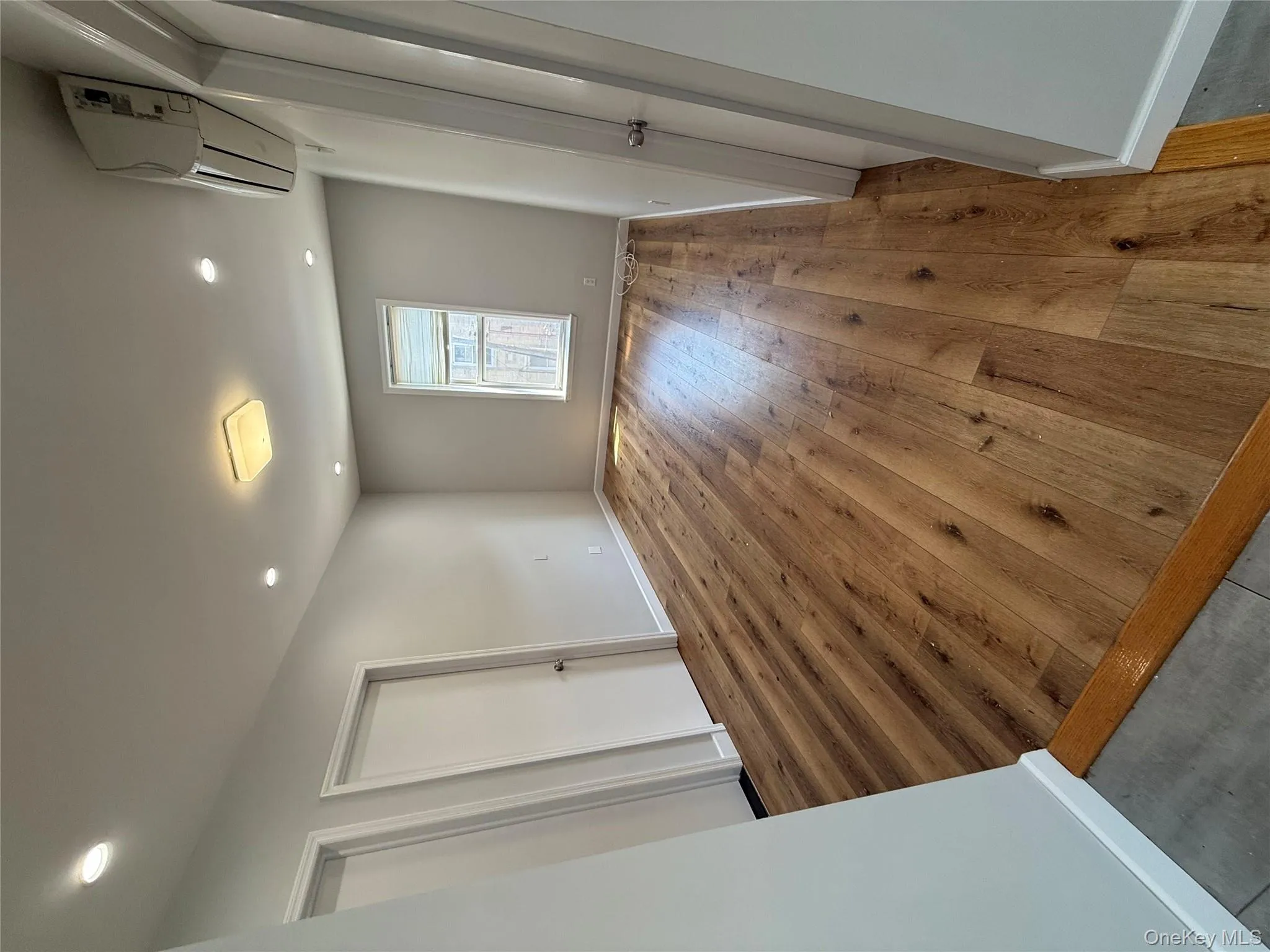 Unfurnished bedroom with light wood-style flooring, recessed lighting, and an AC wall unit Unfurnished bedroom with light wood-style flooring, recessed lighting, and an AC wall unit