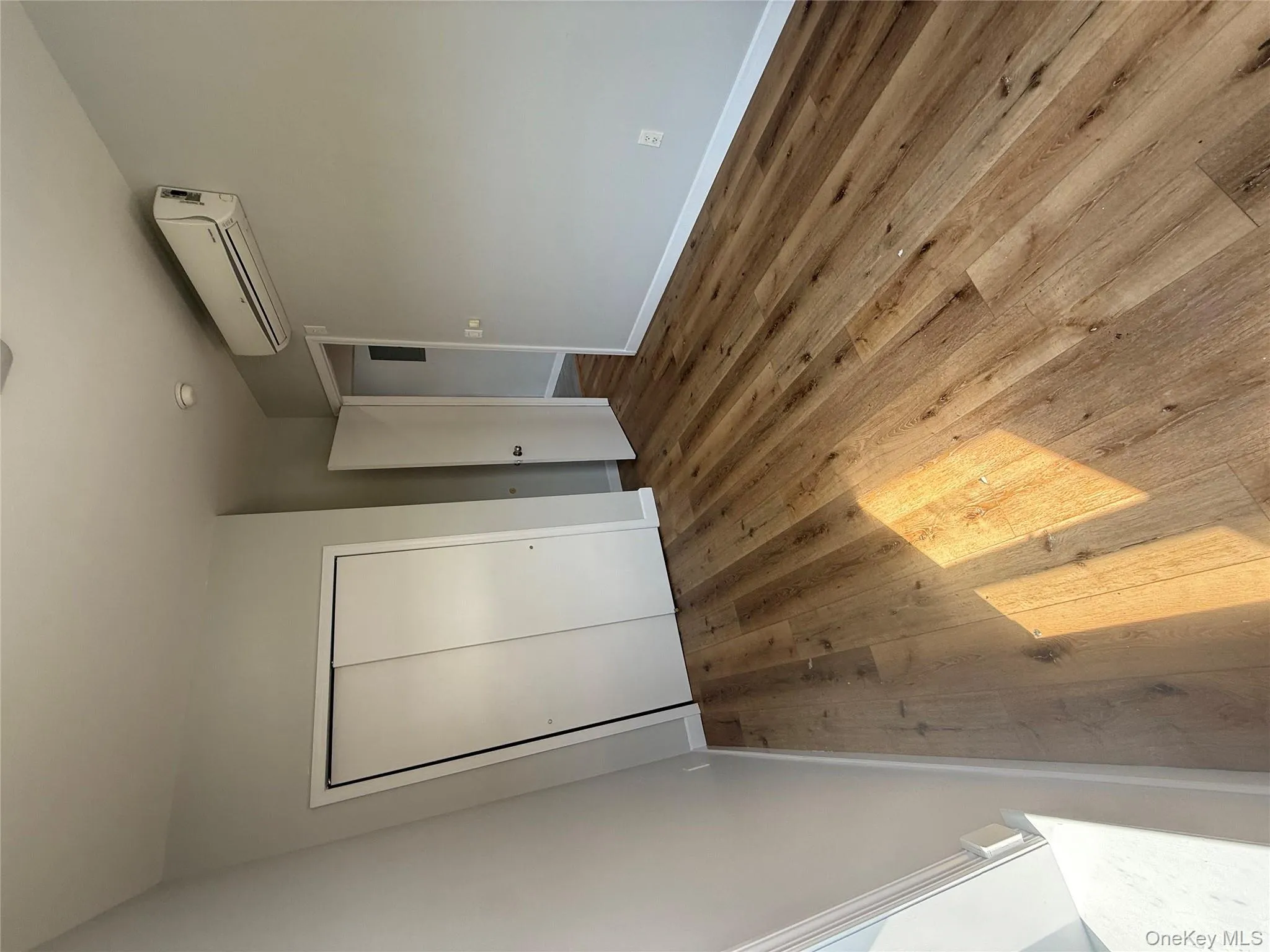 Unfurnished bedroom with hardwood / wood-style floors, a closet, and a wall unit AC Unfurnished bedroom with hardwood / wood-style floors, a closet, and a wall unit AC