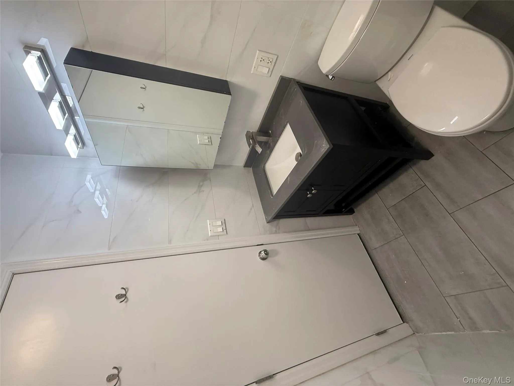 Bathroom with tile walls, vanity, and light tile patterned floors Bathroom with tile walls, vanity, and light tile patterned floors