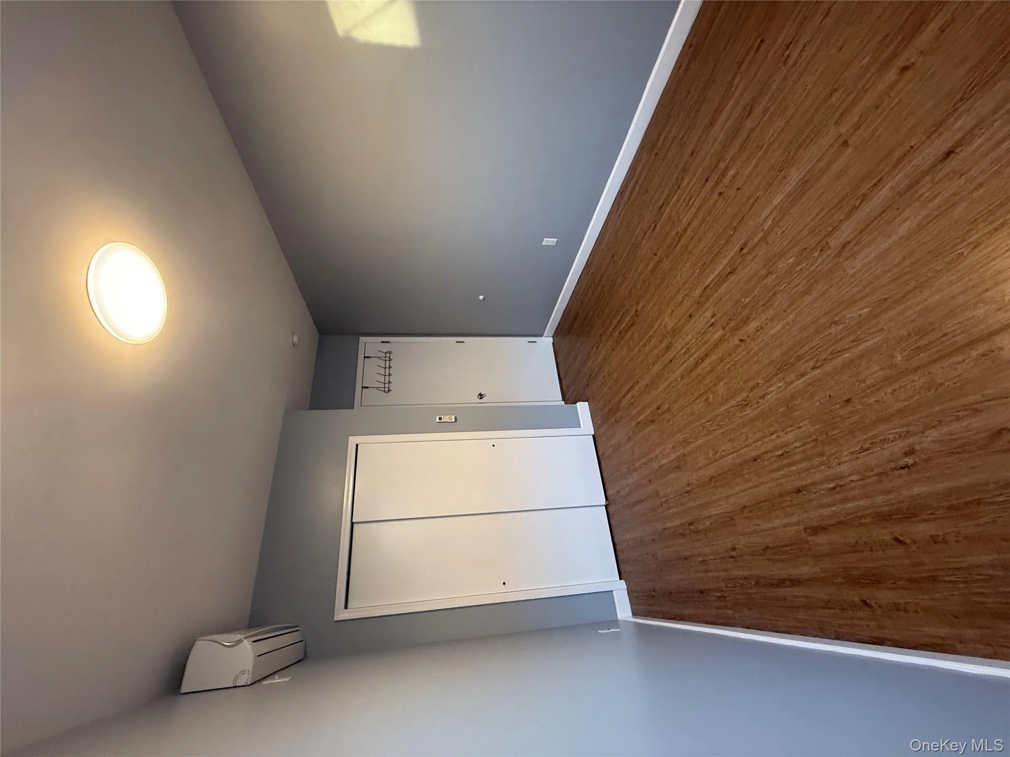 Unfurnished bedroom featuring dark wood finished floors, a closet, and a wall mounted AC Unfurnished bedroom featuring dark wood finished floors, a closet, and a wall mounted AC