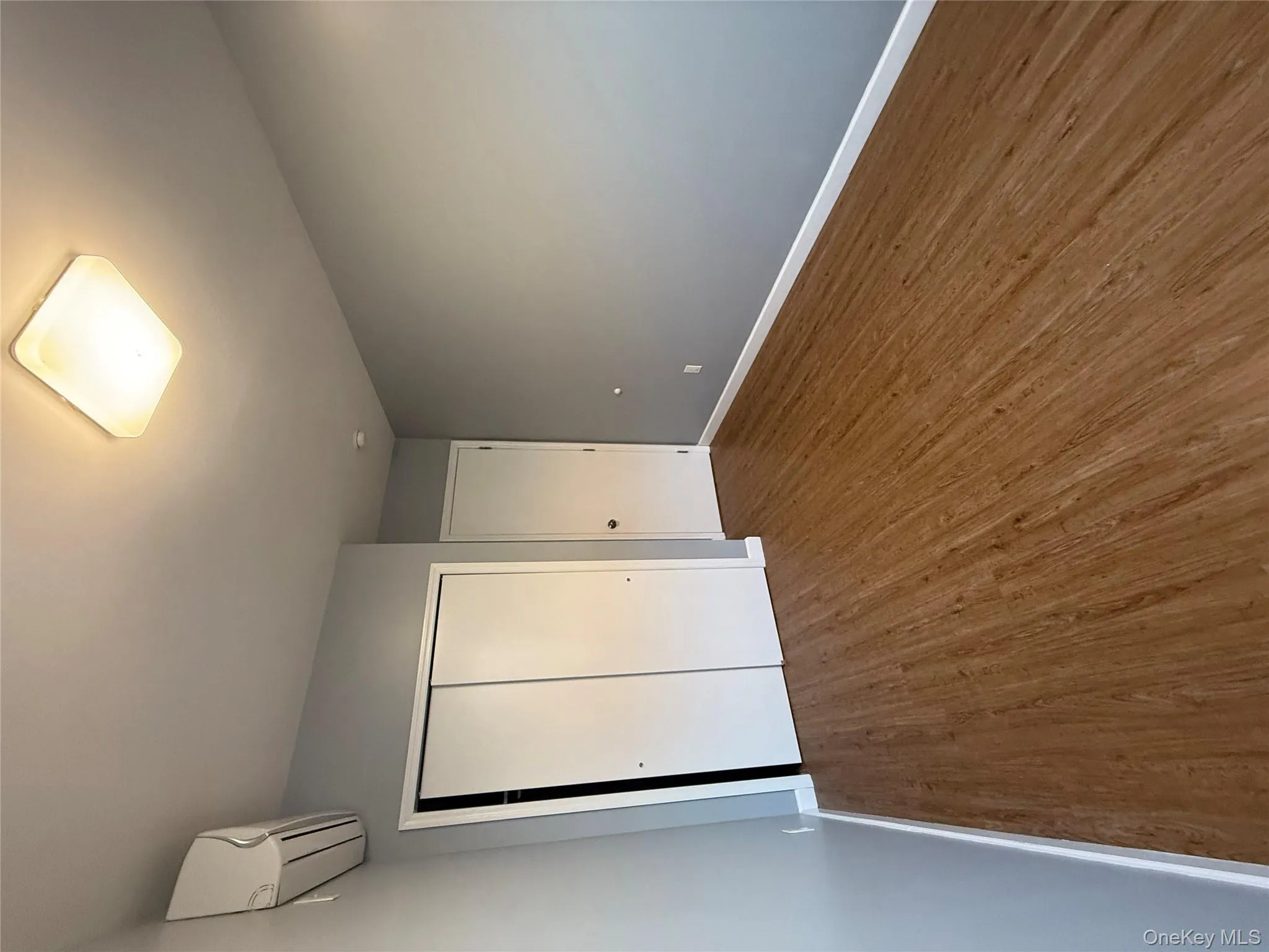 Unfurnished bedroom with a closet, dark wood-style floors, and a wall mounted air conditioner Unfurnished bedroom with a closet, dark wood-style floors, and a wall mounted air conditioner