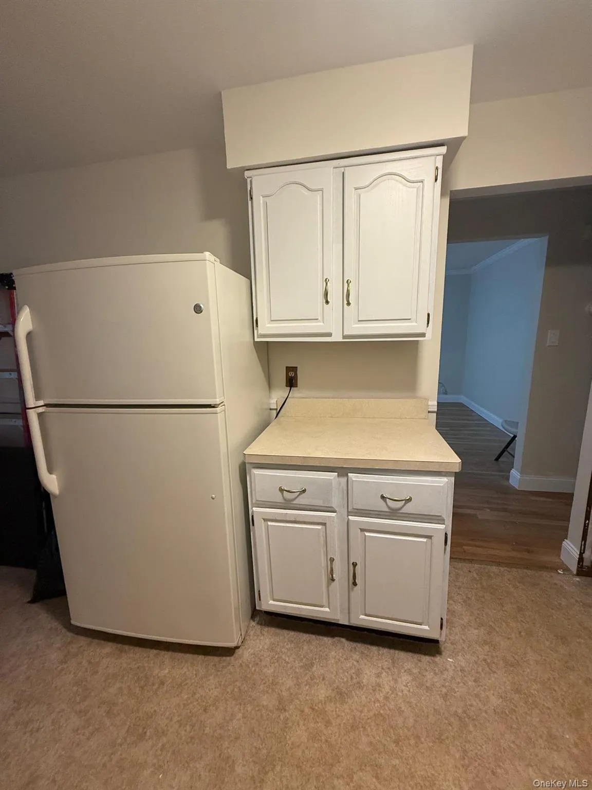 Kitchen featuring freestanding refrigerator, light countertops, and white cabinetry Kitchen featuring freestanding refrigerator, light countertops, and white cabinetry