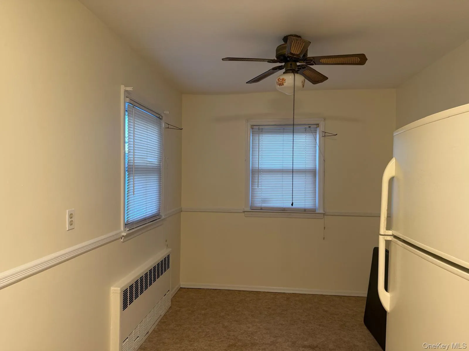 Unfurnished room with radiator heating unit, a ceiling fan, and light carpet Unfurnished room with radiator heating unit, a ceiling fan, and light carpet