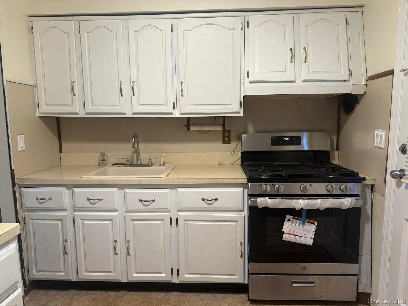 Kitchen with stainless steel gas range oven, white cabinets, and light countertops Kitchen with stainless steel gas range oven, white cabinets, and light countertops