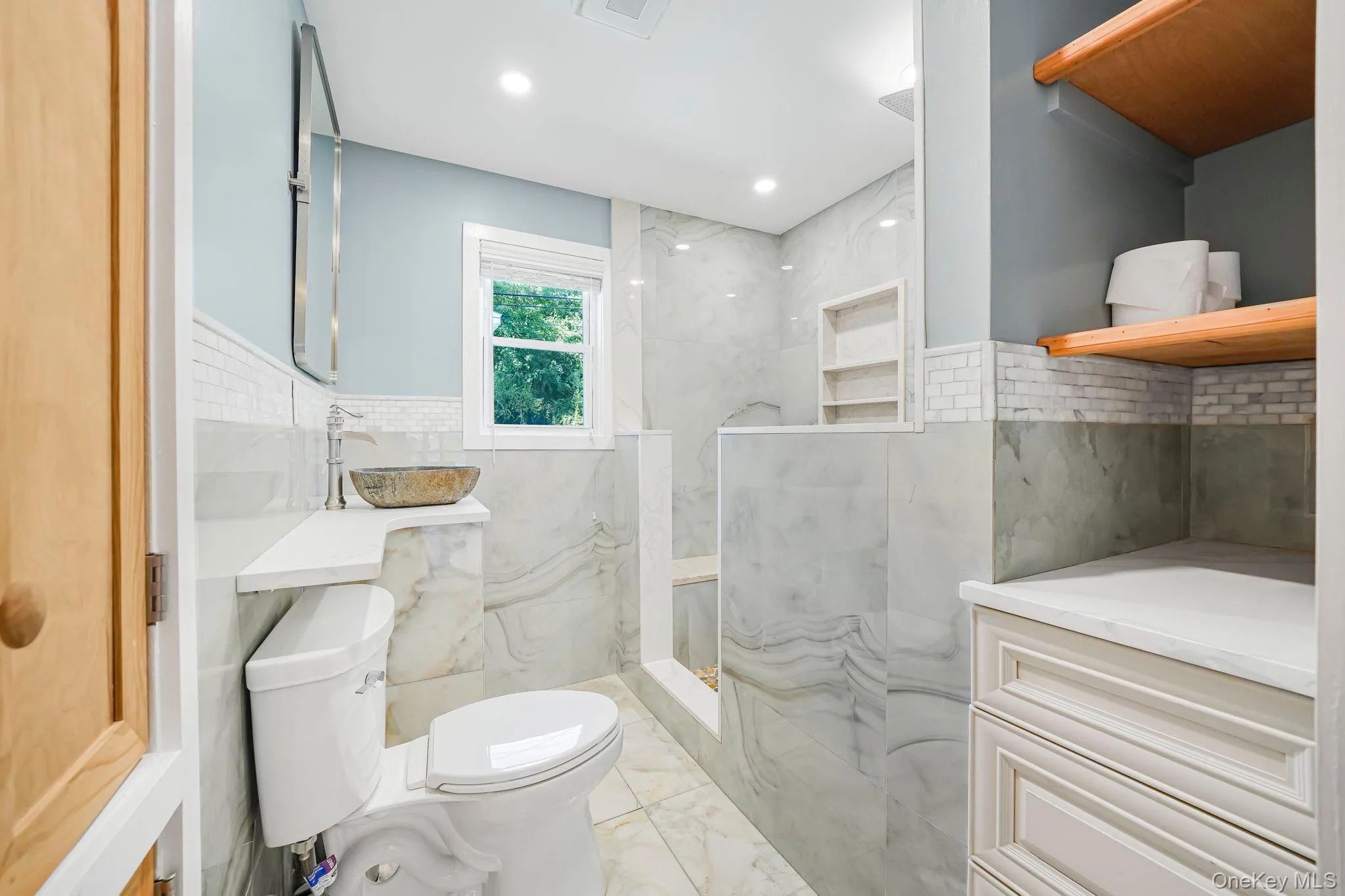 Bathroom with light marble finish floors, tile walls, a marble finish shower, recessed lighting, and decorative backsplash Bathroom with light marble finish floors, tile walls, a marble finish shower, recessed lighting, and decorative backsplash