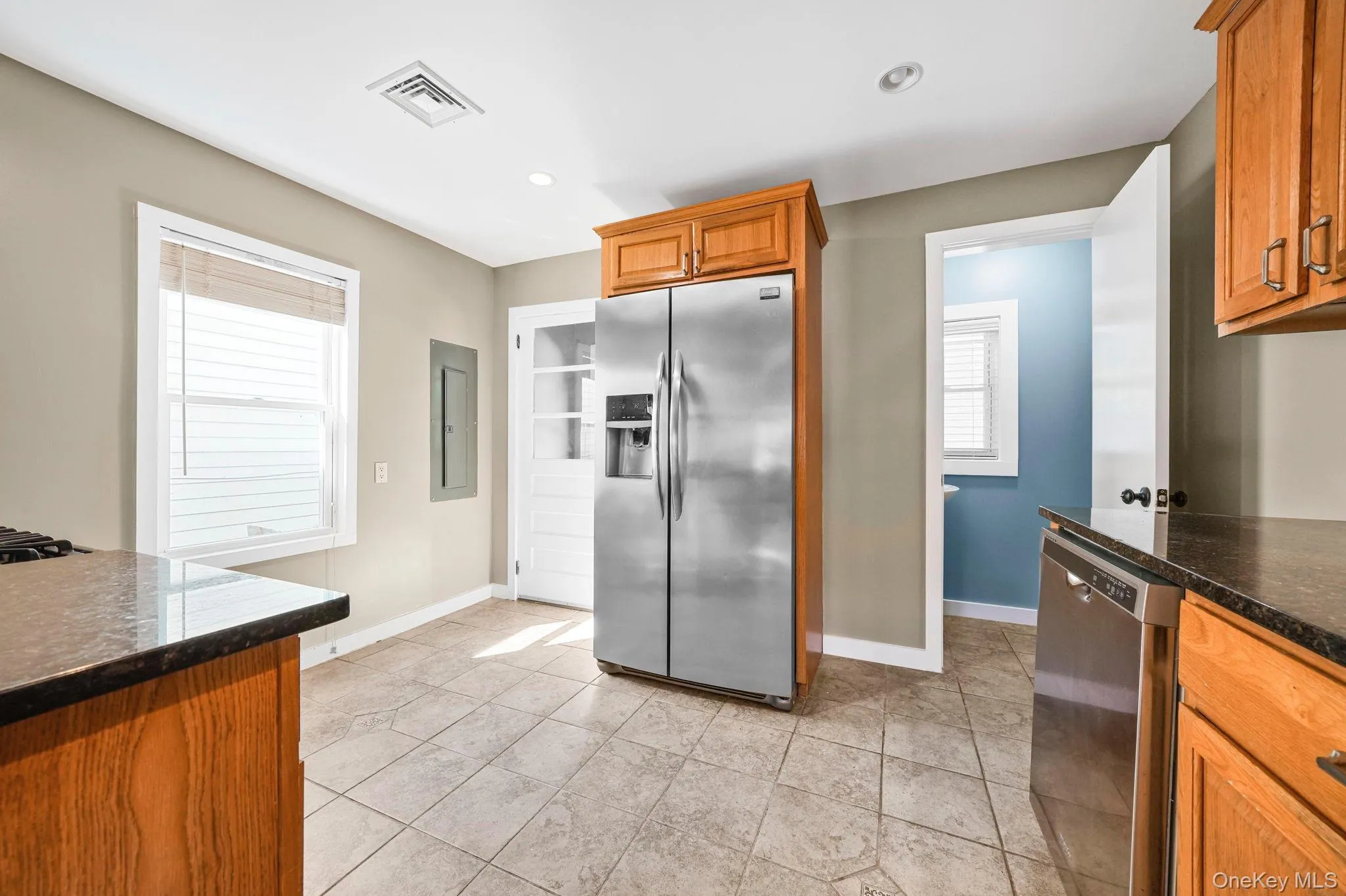 Kitchen with brown cabinets, appliances with stainless steel finishes, dark stone counters, and recessed lighting Kitchen with brown cabinets, appliances with stainless steel finishes, dark stone counters, and recessed lighting
