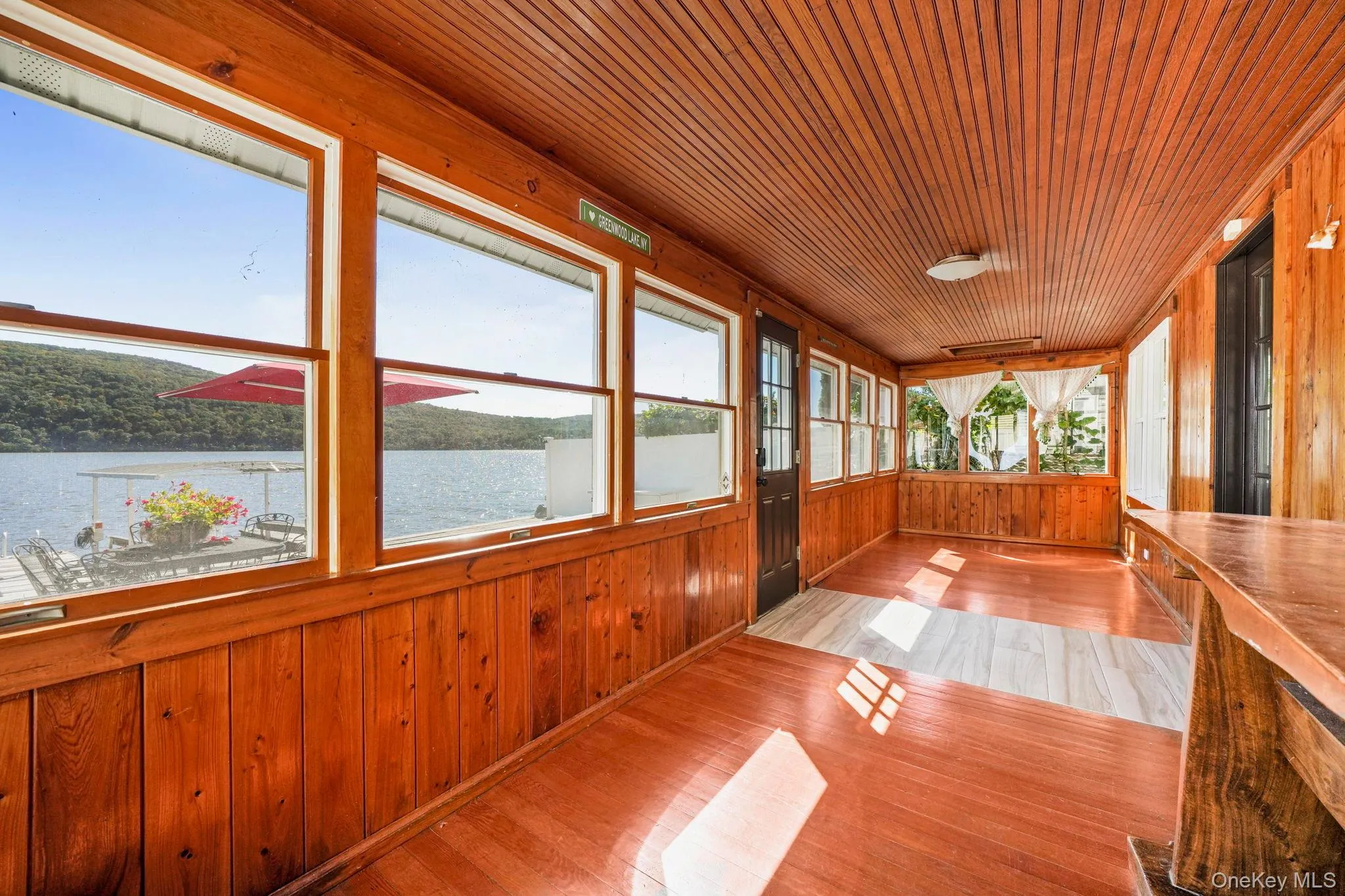 Unfurnished sunroom with wooden walls, a water view, wood finished floors, and wooden ceiling Unfurnished sunroom with wooden walls, a water view, wood finished floors, and wooden ceiling