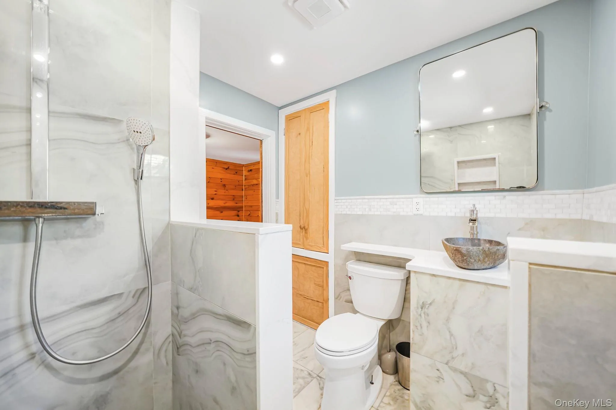Full bath with vanity, a marble finish shower, recessed lighting, and tile walls Full bath with vanity, a marble finish shower, recessed lighting, and tile walls