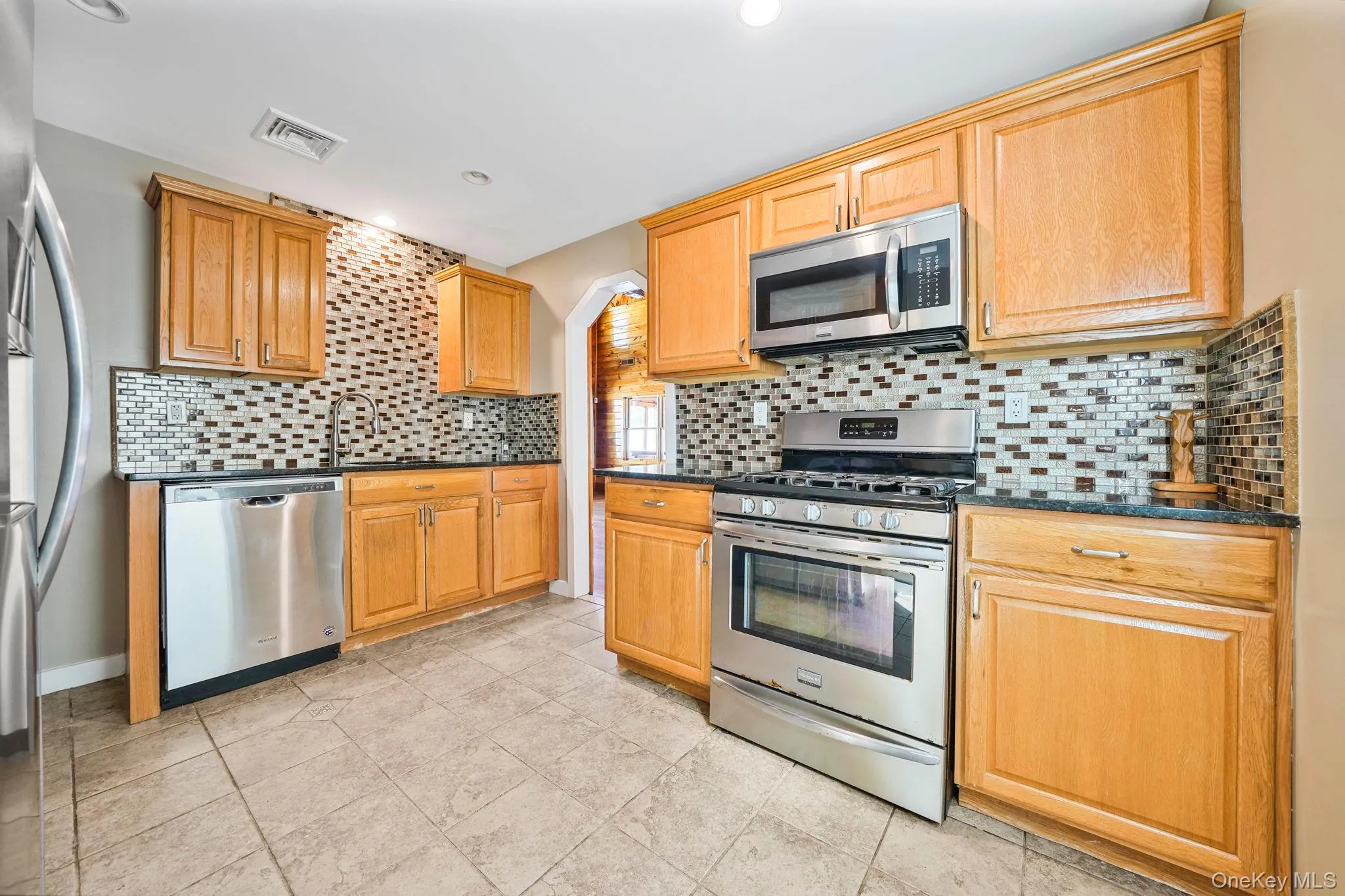 Kitchen featuring stainless steel appliances, decorative backsplash, light tile patterned floors, and recessed lighting Kitchen featuring stainless steel appliances, decorative backsplash, light tile patterned floors, and recessed lighting