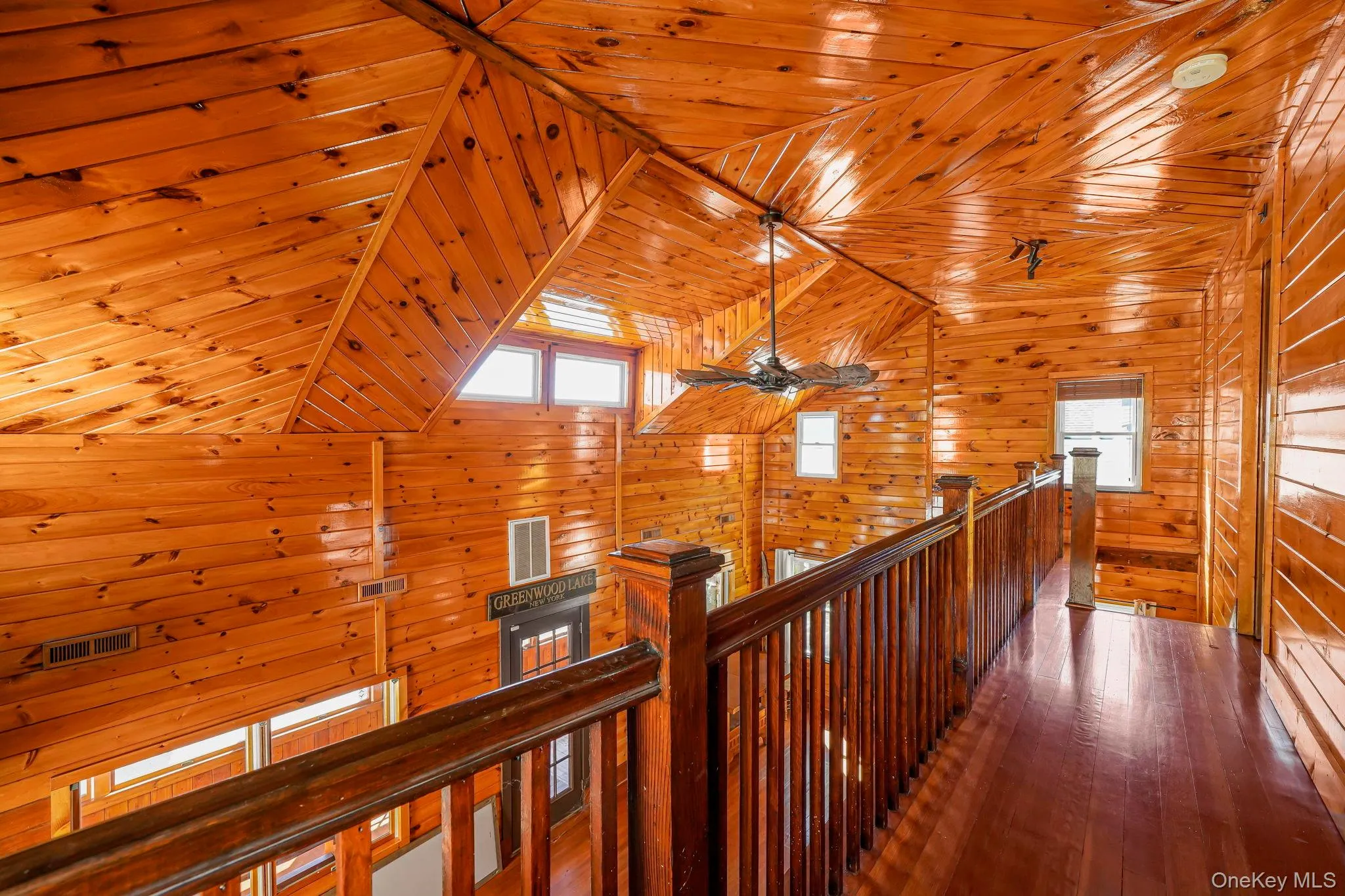 Hall with wooden ceiling, wooden walls, an upstairs landing, vaulted ceiling, and hardwood / wood-style flooring Hall with wooden ceiling, wooden walls, an upstairs landing, vaulted ceiling, and hardwood / wood-style flooring