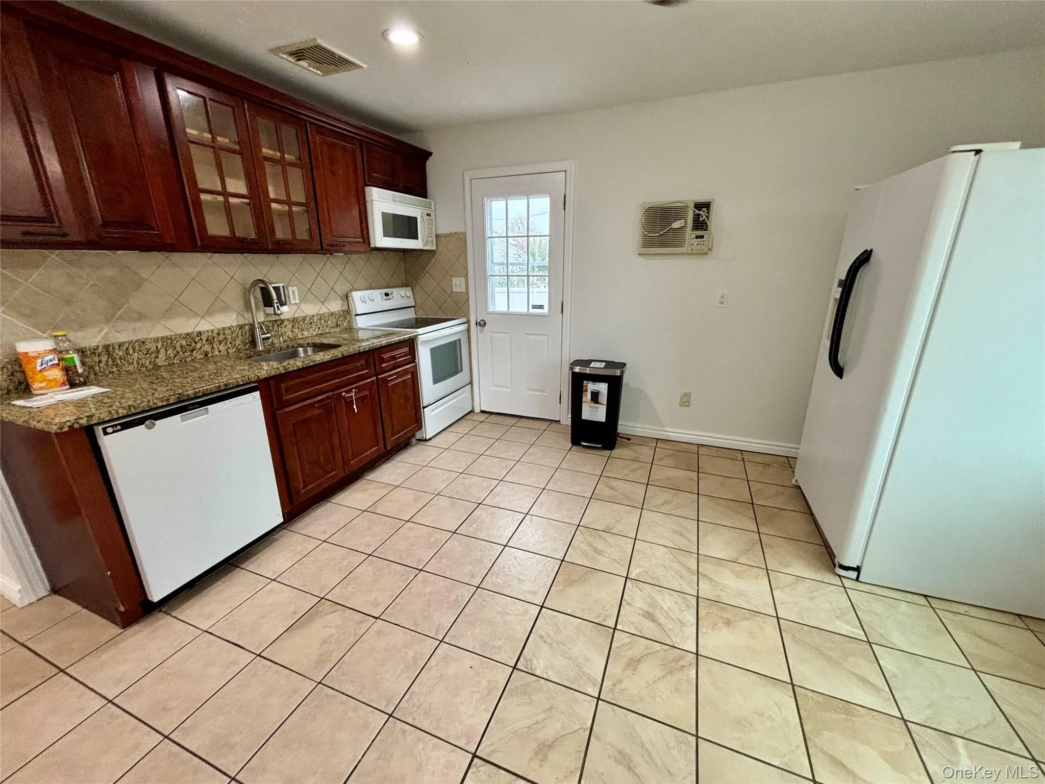 Kitchen with white appliances, decorative backsplash, glass insert cabinets, light tile patterned floors, and recessed lighting Kitchen with white appliances, decorative backsplash, glass insert cabinets, light tile patterned floors, and recessed lighting