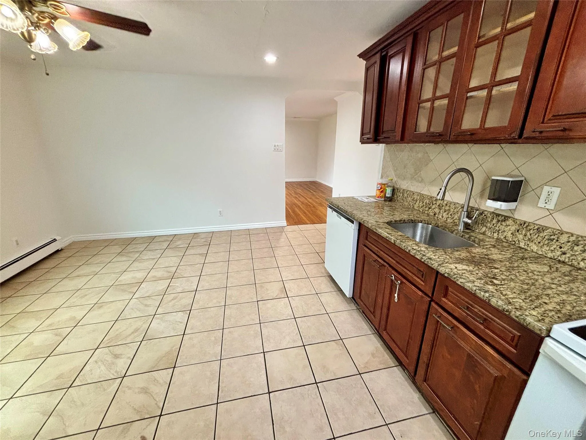 Kitchen featuring light stone counters, glass insert cabinets, light tile patterned floors, recessed lighting, and white dishwasher Kitchen featuring light stone counters, glass insert cabinets, light tile patterned floors, recessed lighting, and white dishwasher