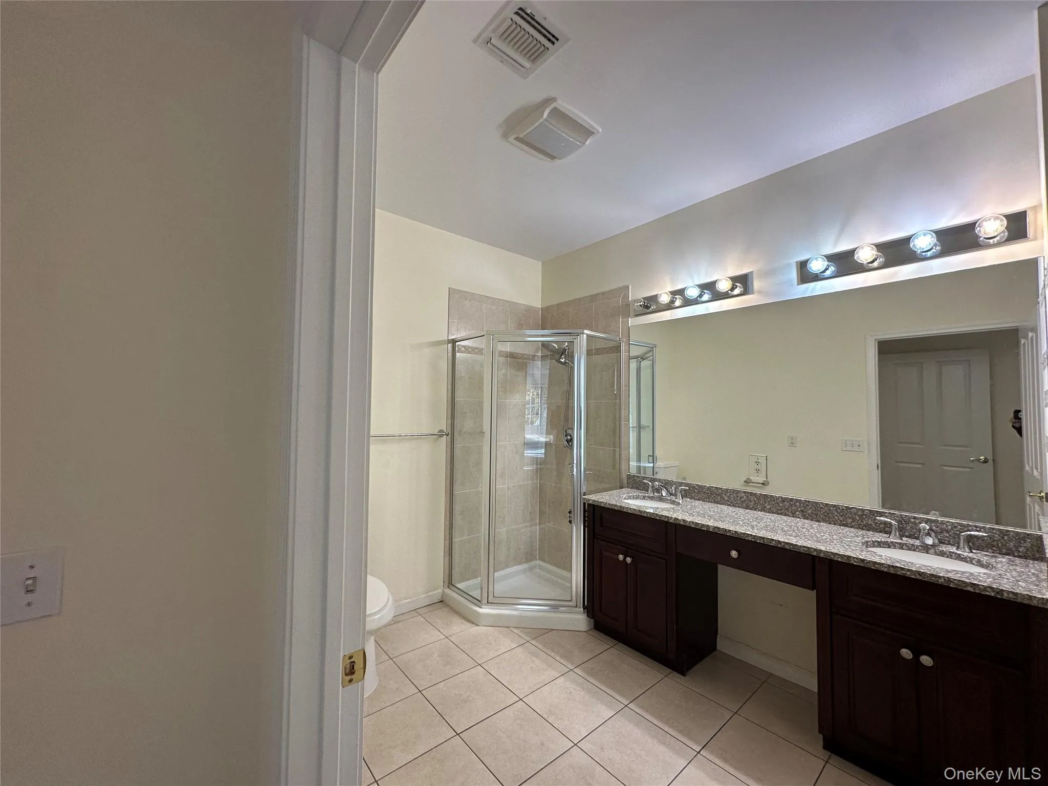 Full bathroom with light tile patterned floors, a stall shower, and double vanity Full bathroom with light tile patterned floors, a stall shower, and double vanity