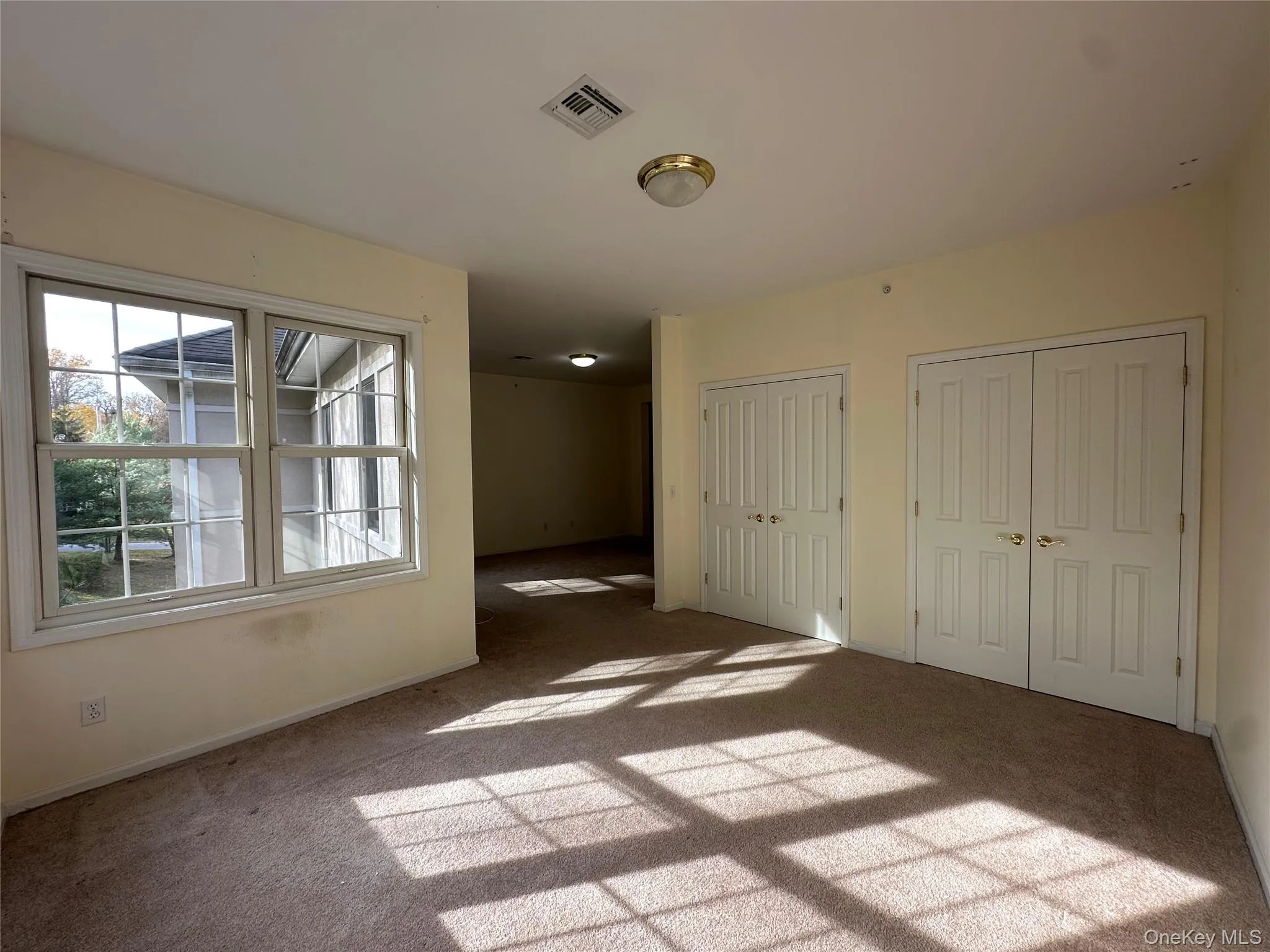 Unfurnished bedroom featuring two closets and light carpet Unfurnished bedroom featuring two closets and light carpet