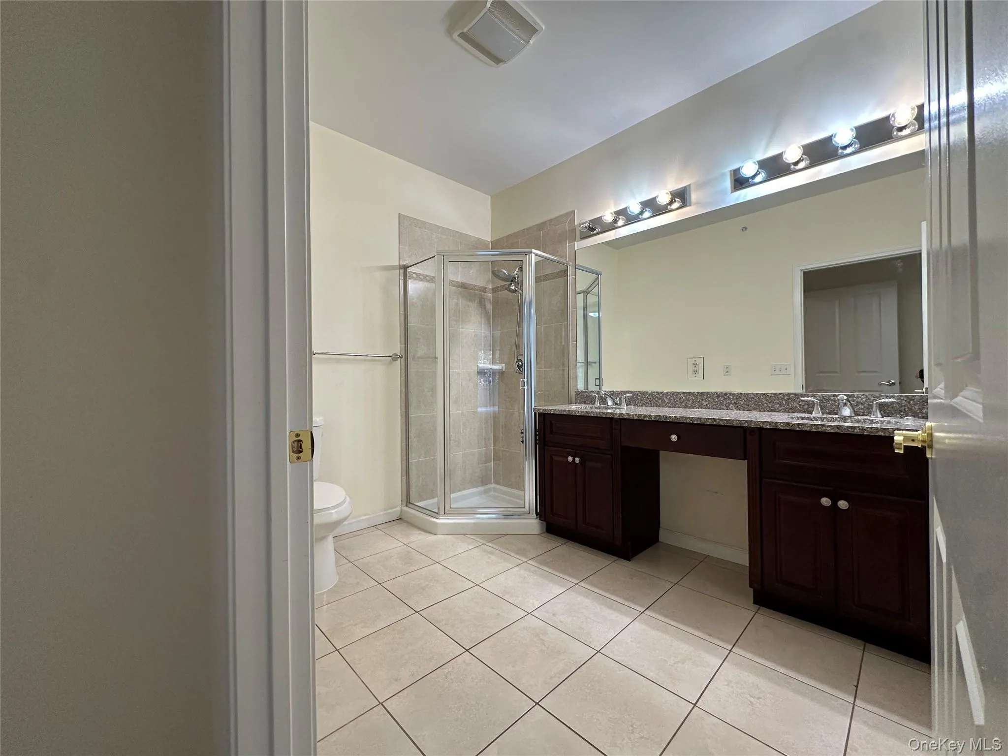 Bathroom with a shower stall, light tile patterned flooring, and double vanity Bathroom with a shower stall, light tile patterned flooring, and double vanity