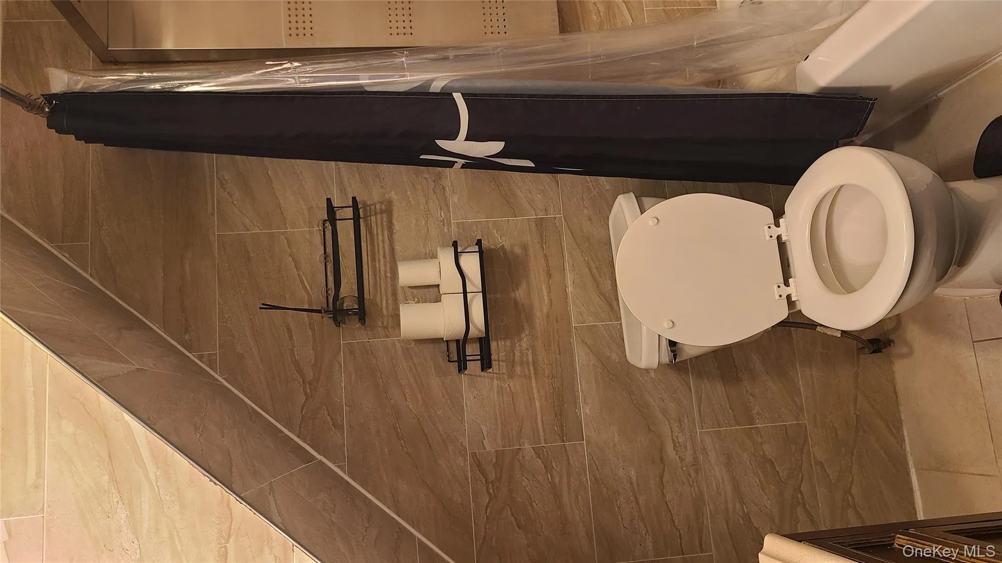 Full bath featuring shower / bath combo with shower curtain, light tile patterned floors, and tile walls Full bath featuring shower / bath combo with shower curtain, light tile patterned floors, and tile walls