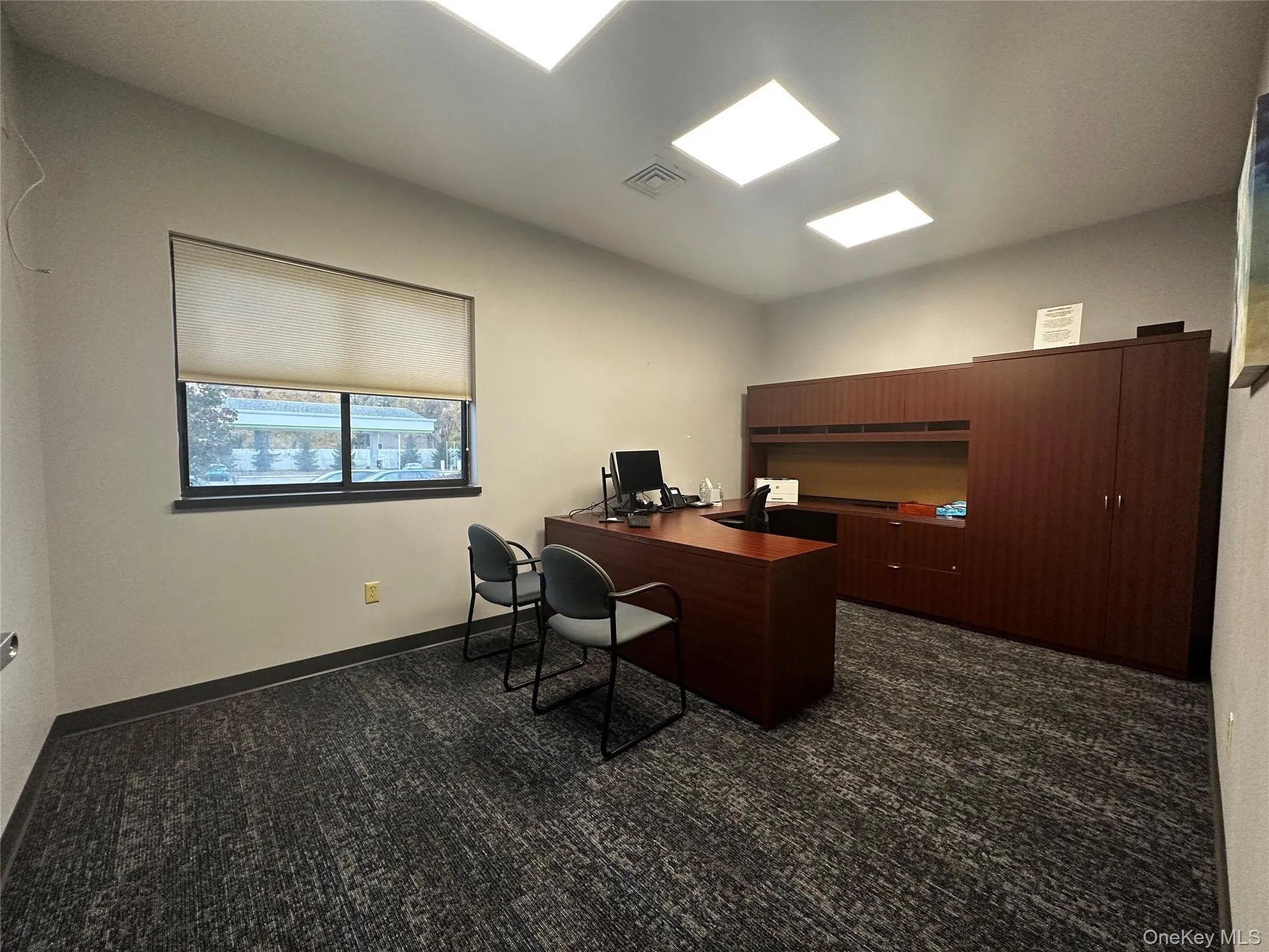 Office space featuring dark colored carpet and baseboards Office space featuring dark colored carpet and baseboards