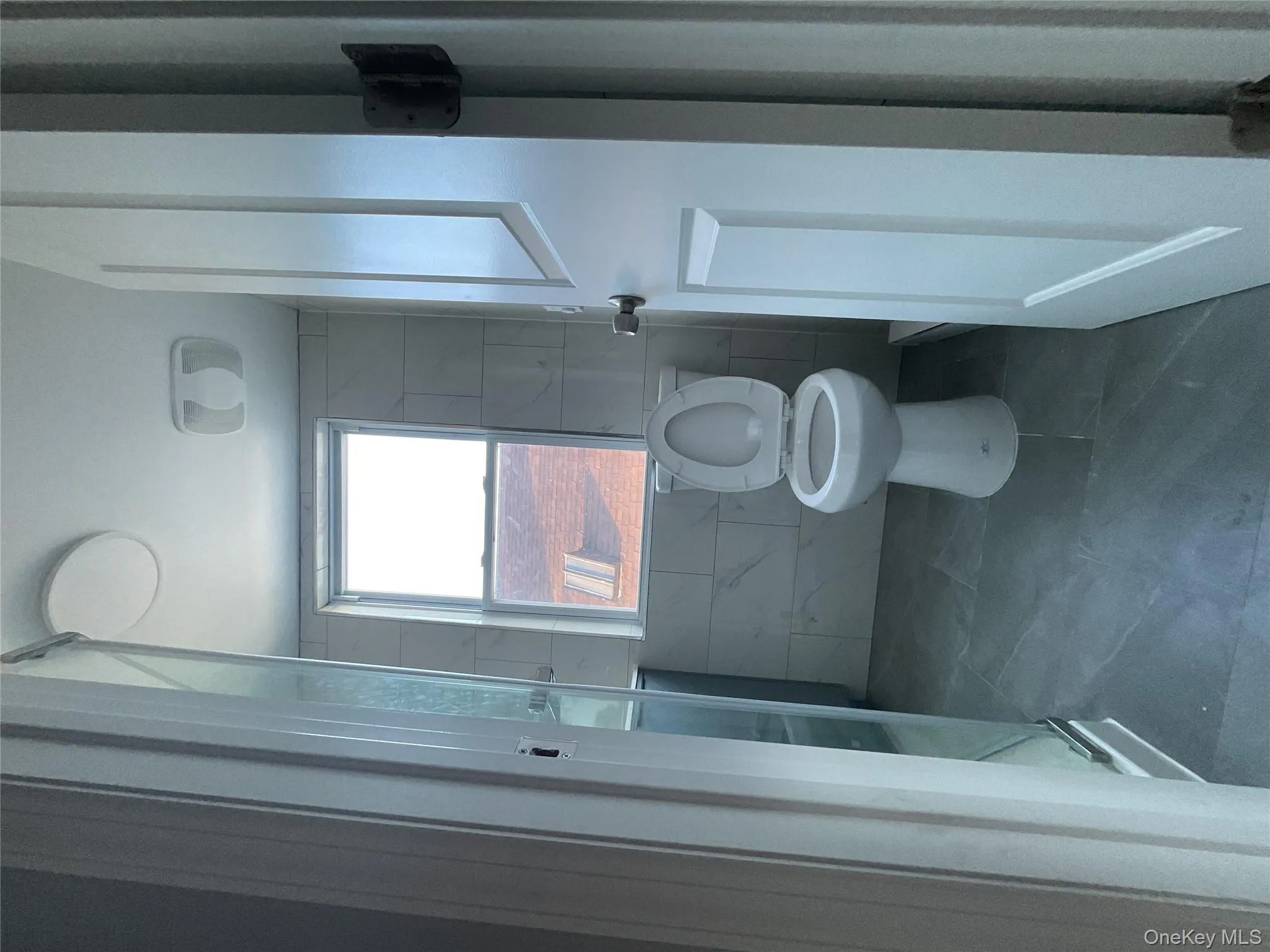 Bathroom with tile walls, a shower stall, tile patterned flooring, and baseboard heating Bathroom with tile walls, a shower stall, tile patterned flooring, and baseboard heating