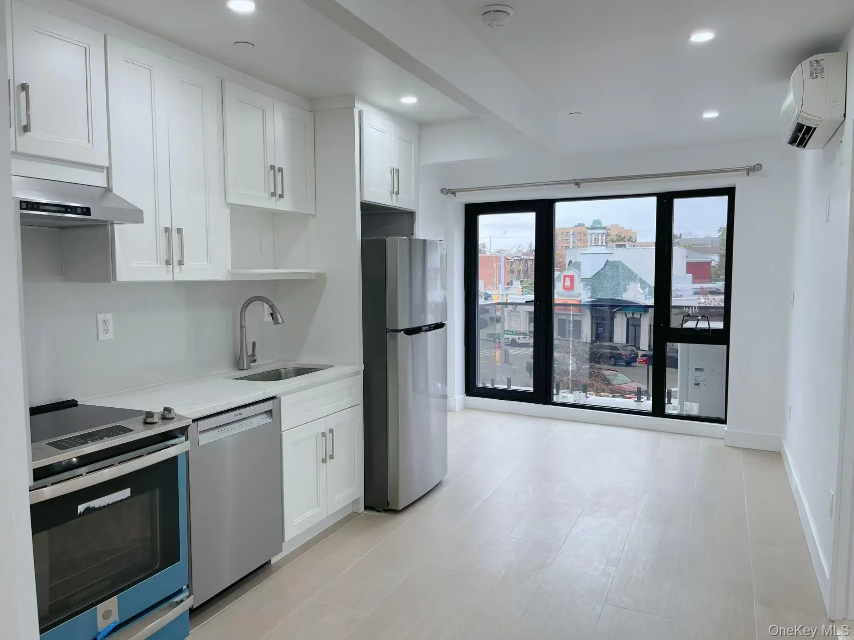 Kitchen with appliances with stainless steel finishes, white cabinets, recessed lighting, light stone countertops, and a wall mounted AC Kitchen with appliances with stainless steel finishes, white cabinets, recessed lighting, light stone countertops, and a wall mounted AC