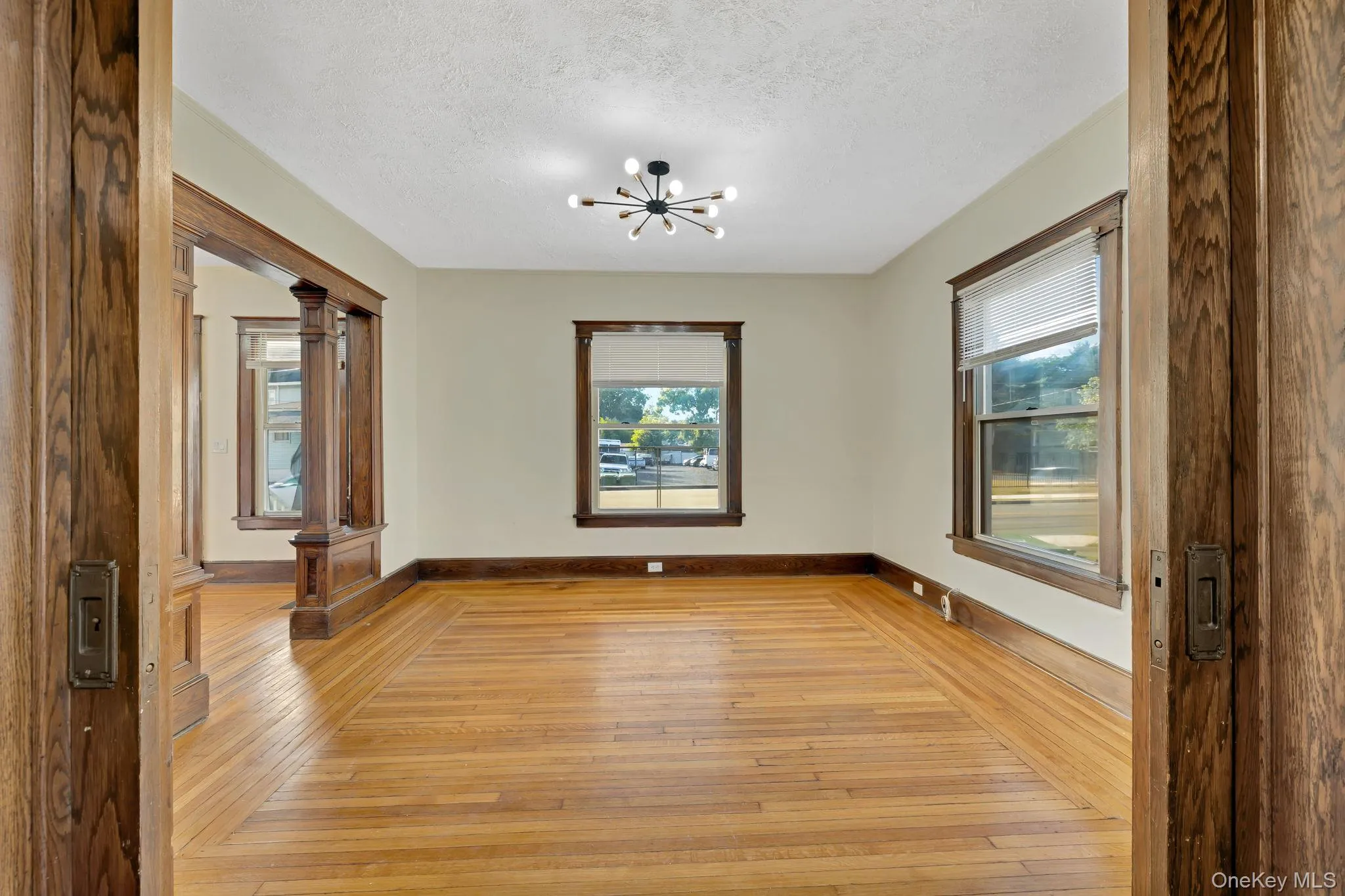 Empty room featuring a chandelier, light wood-style floors, and a textured ceiling Empty room featuring a chandelier, light wood-style floors, and a textured ceiling
