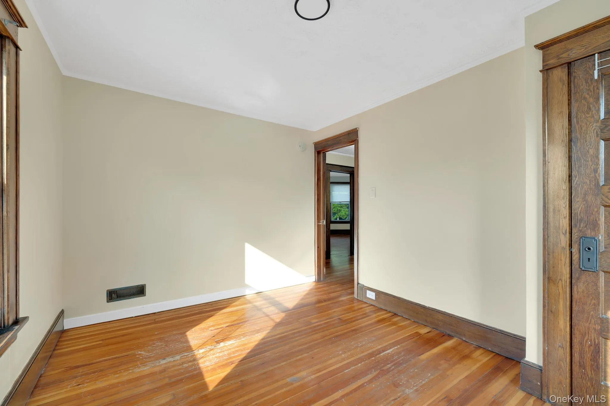 Unfurnished room with hardwood / wood-style floors, a baseboard radiator, and ornamental molding Unfurnished room with hardwood / wood-style floors, a baseboard radiator, and ornamental molding
