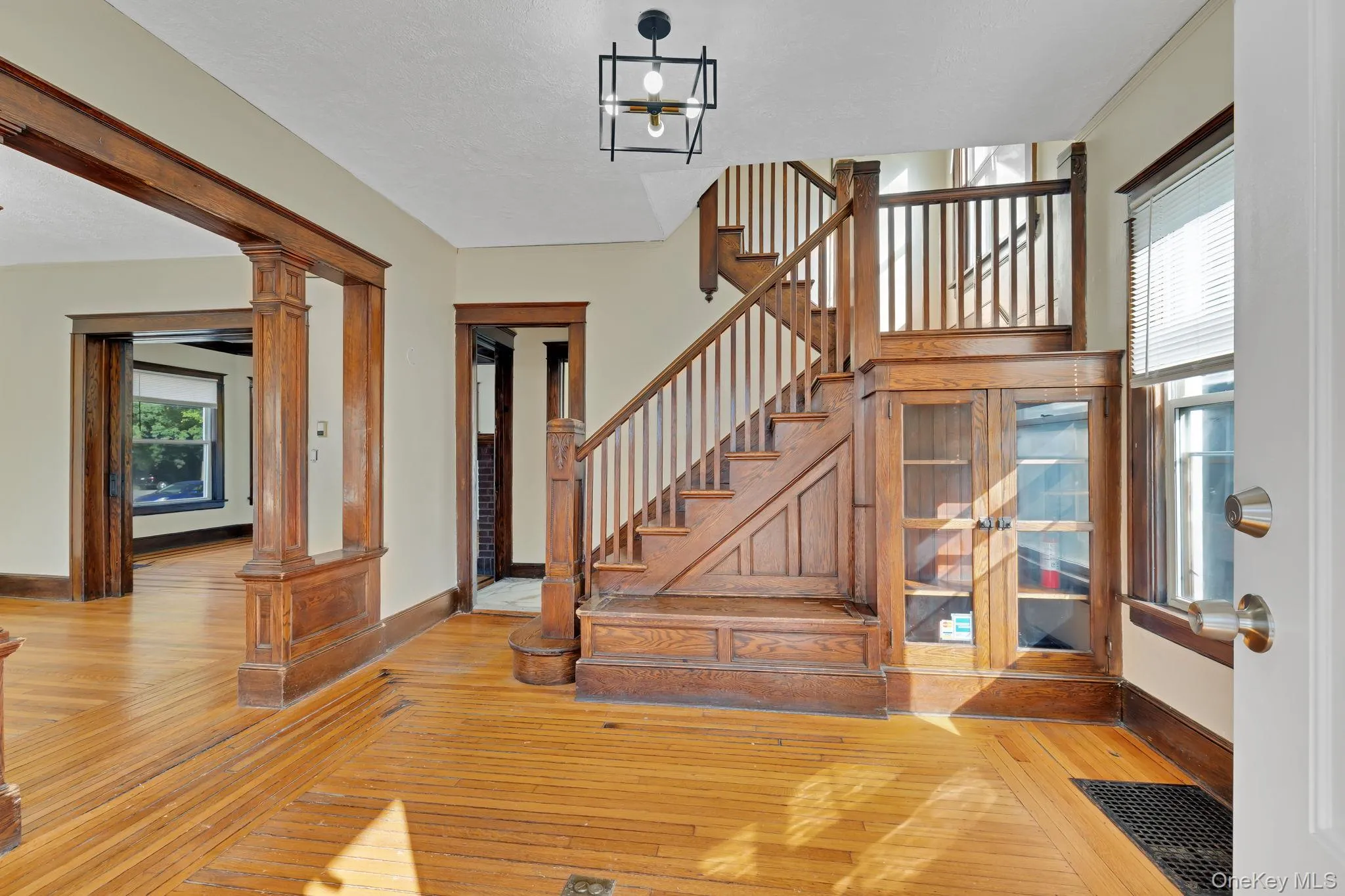 Stairs with healthy amount of natural light, hardwood / wood-style floors, and ornate columns Stairs with healthy amount of natural light, hardwood / wood-style floors, and ornate columns