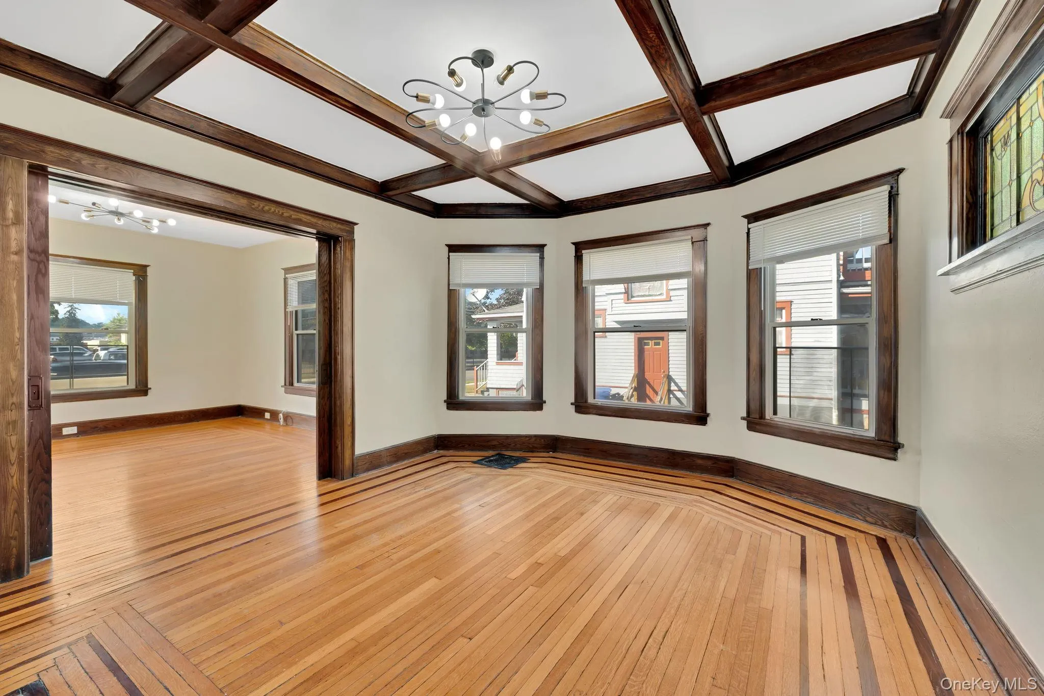 Empty room with a chandelier, light wood-style flooring, coffered ceiling, healthy amount of natural light, and beam ceiling Empty room with a chandelier, light wood-style flooring, coffered ceiling, healthy amount of natural light, and beam ceiling