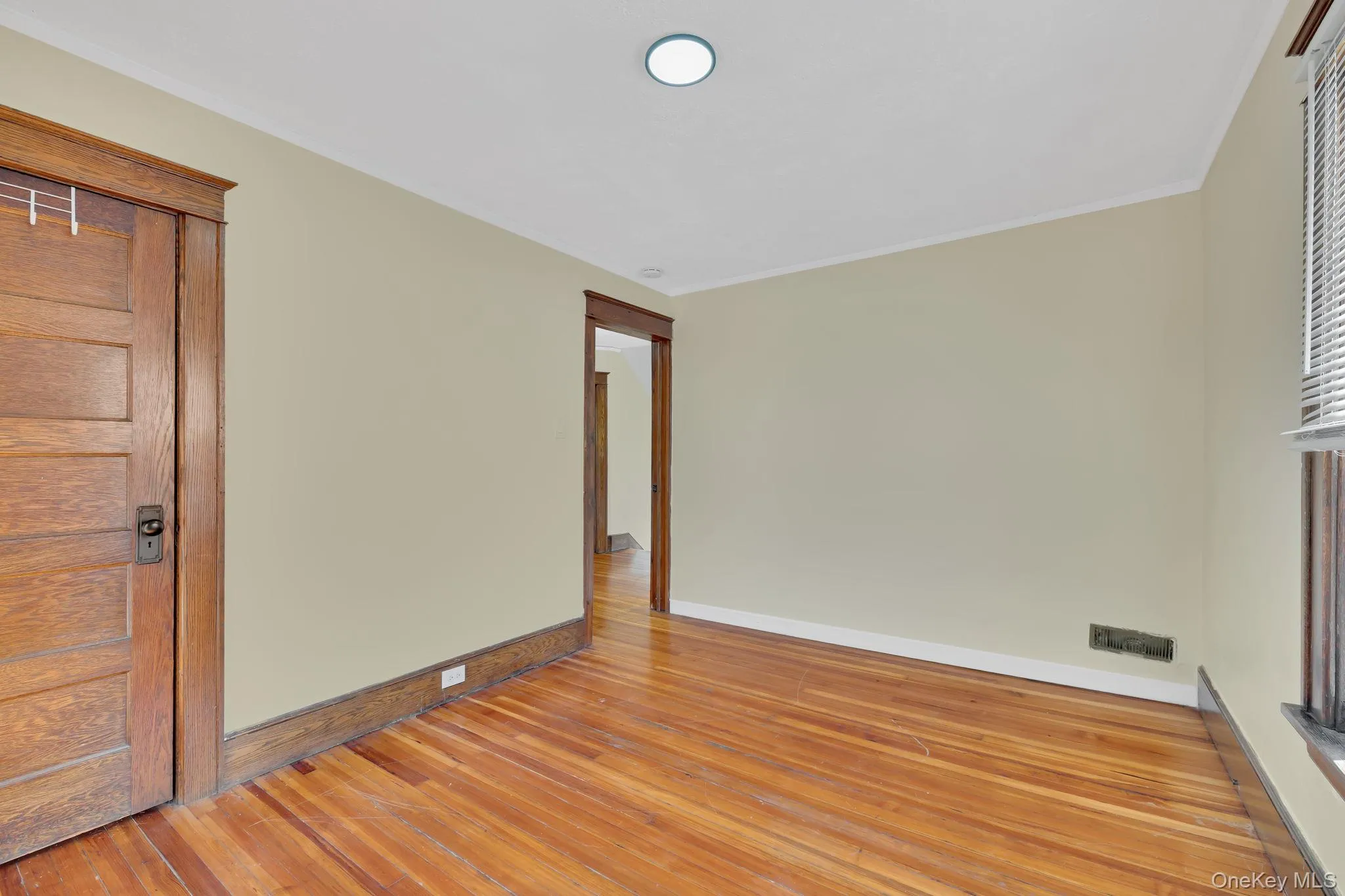 Empty room with light wood-style floors, crown molding, and a baseboard radiator Empty room with light wood-style floors, crown molding, and a baseboard radiator