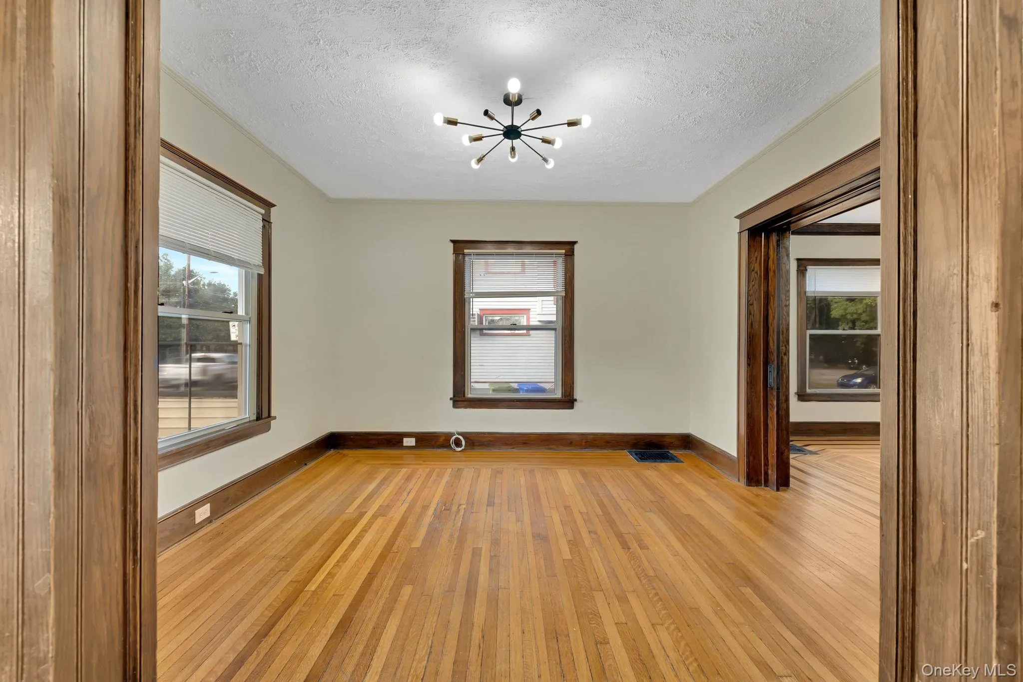Spare room with light wood-style flooring, a chandelier, and a textured ceiling Spare room with light wood-style flooring, a chandelier, and a textured ceiling