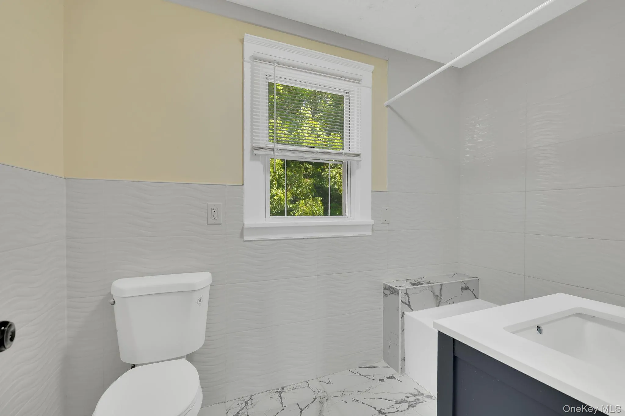 Half bathroom featuring vanity, light marble finish floors, and tile walls Half bathroom featuring vanity, light marble finish floors, and tile walls