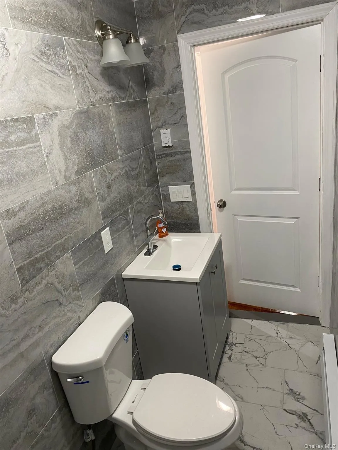 Bathroom with tile walls, light marble finish floors, and vanity Bathroom with tile walls, light marble finish floors, and vanity