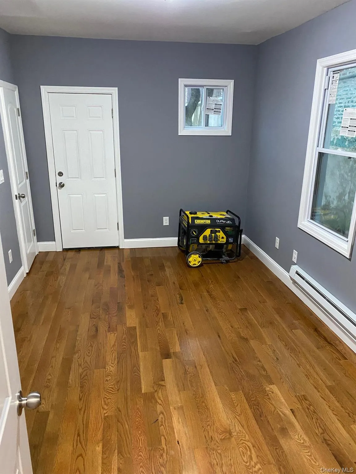 Empty room featuring a baseboard heating unit and dark wood finished floors Empty room featuring a baseboard heating unit and dark wood finished floors