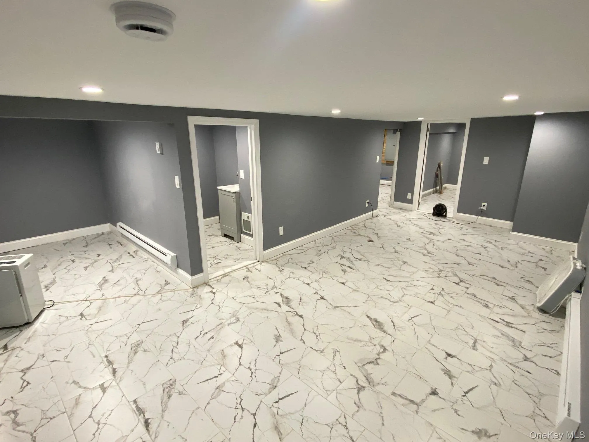 Finished basement featuring light marble finish floors, recessed lighting, and baseboard heating Finished basement featuring light marble finish floors, recessed lighting, and baseboard heating