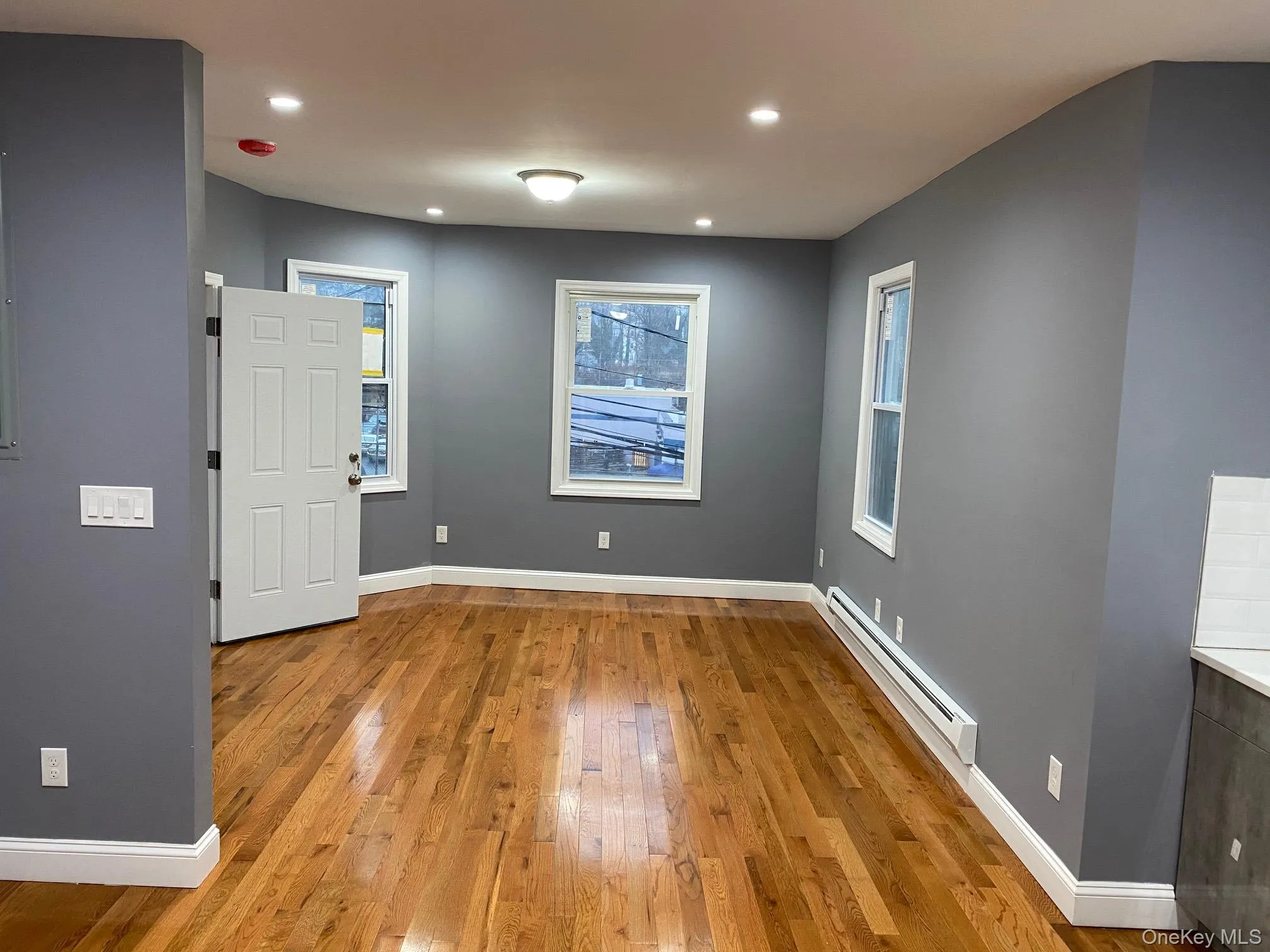 Unfurnished room with a baseboard heating unit, light wood-type flooring, and recessed lighting Unfurnished room with a baseboard heating unit, light wood-type flooring, and recessed lighting