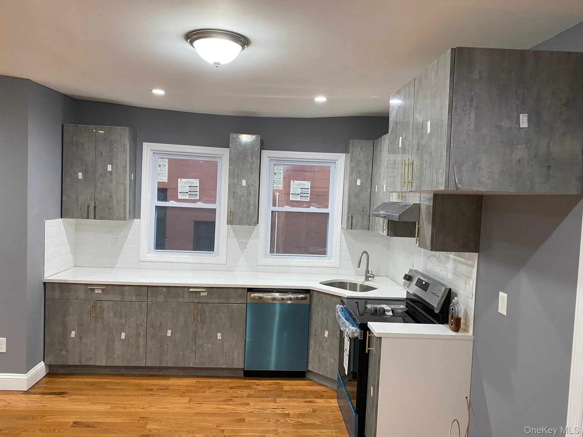 Kitchen with range with electric stovetop, modern cabinets, stainless steel dishwasher, light wood finished floors, and under cabinet range hood Kitchen with range with electric stovetop, modern cabinets, stainless steel dishwasher, light wood finished floors, and under cabinet range hood