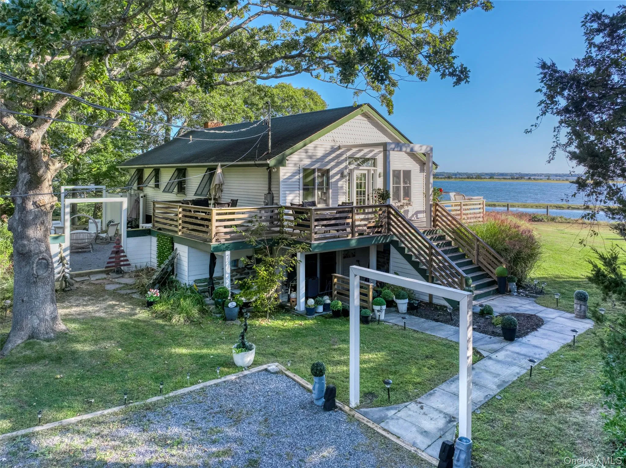 Rear view of house featuring stairs, a yard, and a deck with water view Rear view of house featuring stairs, a yard, and a deck with water view