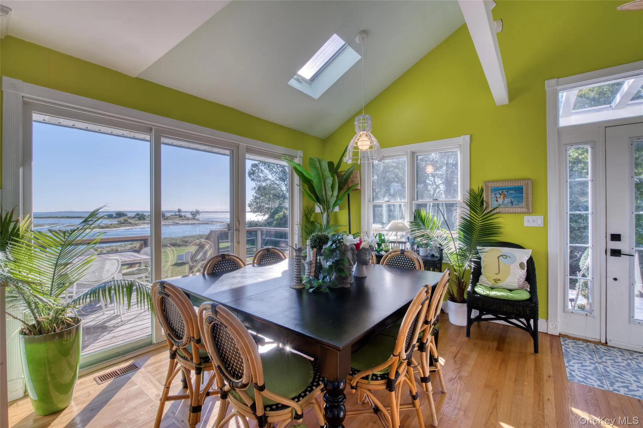 Dining area featuring a water view, a skylight, light wood-style floors, and high vaulted ceiling Dining area featuring a water view, a skylight, light wood-style floors, and high vaulted ceiling