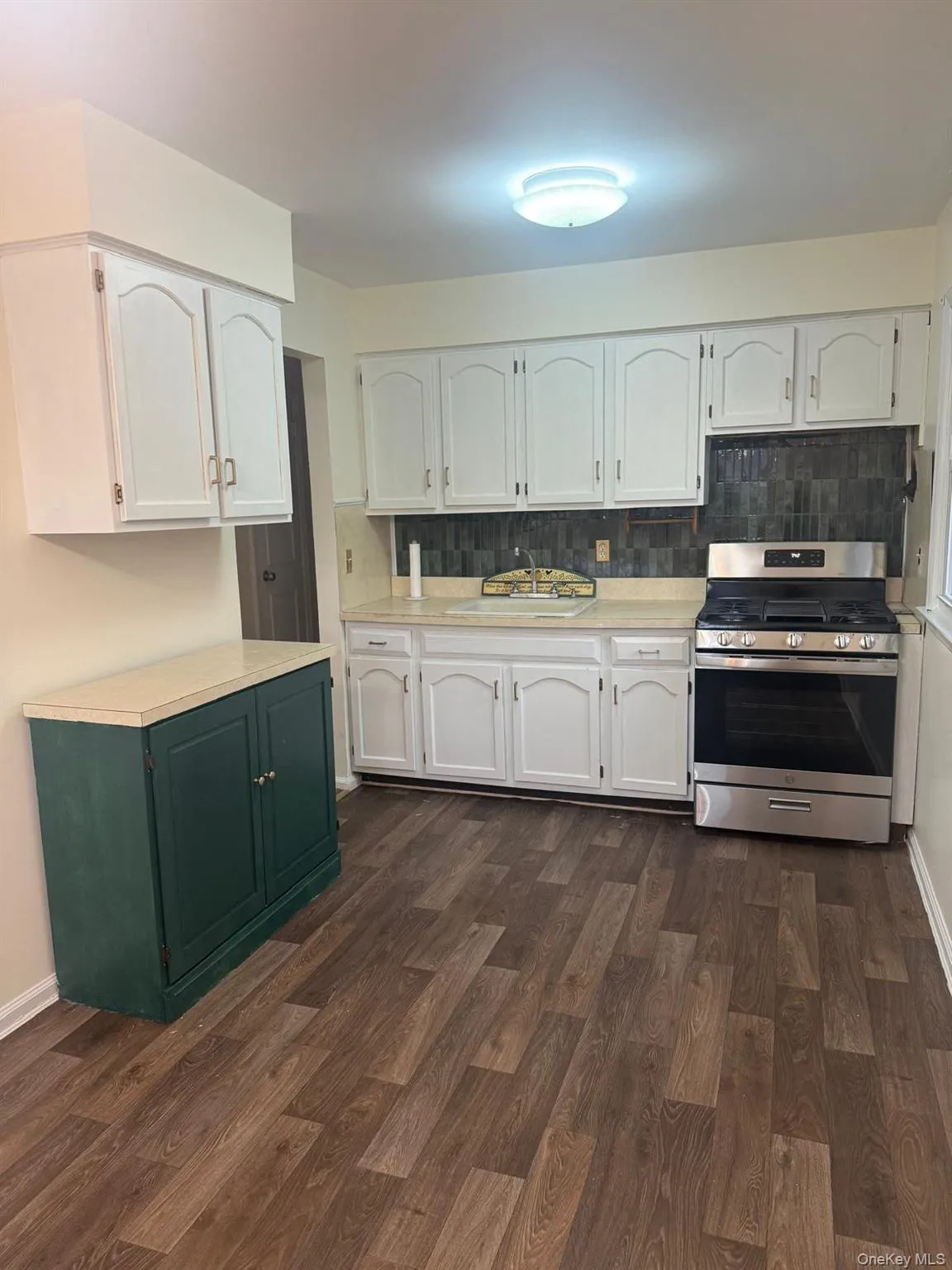 Kitchen featuring white cabinetry, stainless steel gas range, backsplash, and light countertops Kitchen featuring white cabinetry, stainless steel gas range, backsplash, and light countertops