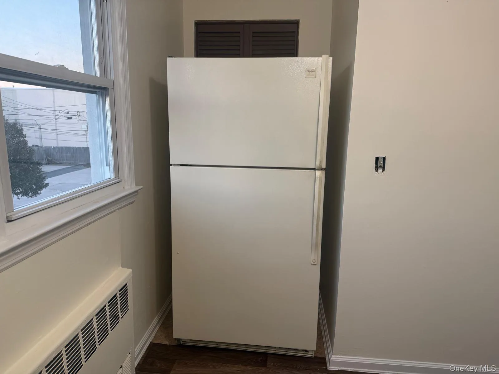 Kitchen view of freestanding refrigerator, dark wood finished floors, and radiator heating unit Kitchen view of freestanding refrigerator, dark wood finished floors, and radiator heating unit