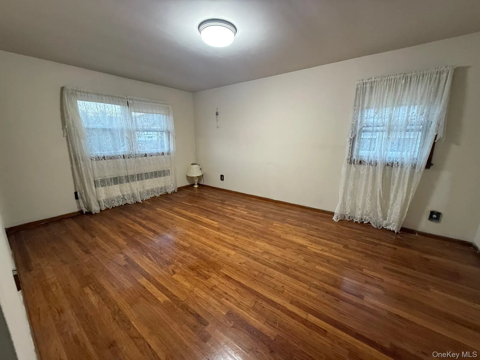 Spare room featuring dark wood finished floors and radiator heating unit Spare room featuring dark wood finished floors and radiator heating unit