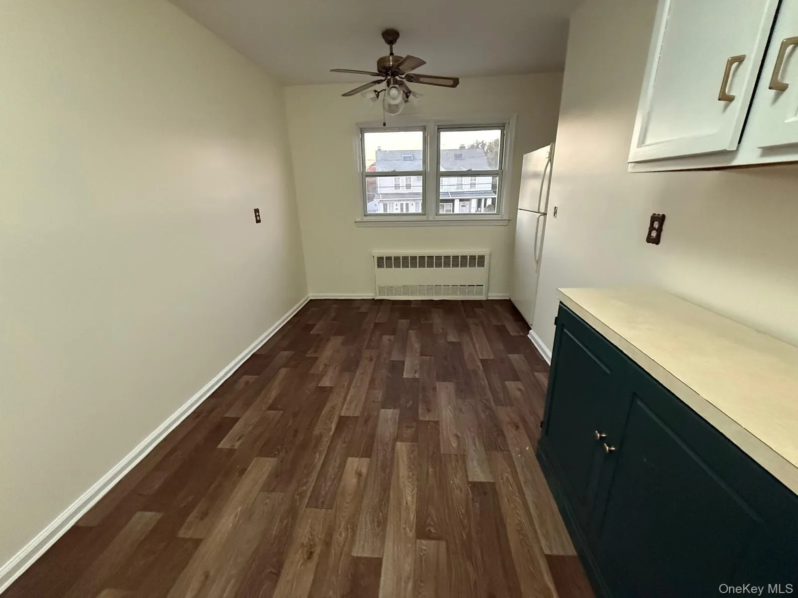 Unfurnished dining area featuring radiator heating unit, dark wood finished floors, and a ceiling fan Unfurnished dining area featuring radiator heating unit, dark wood finished floors, and a ceiling fan