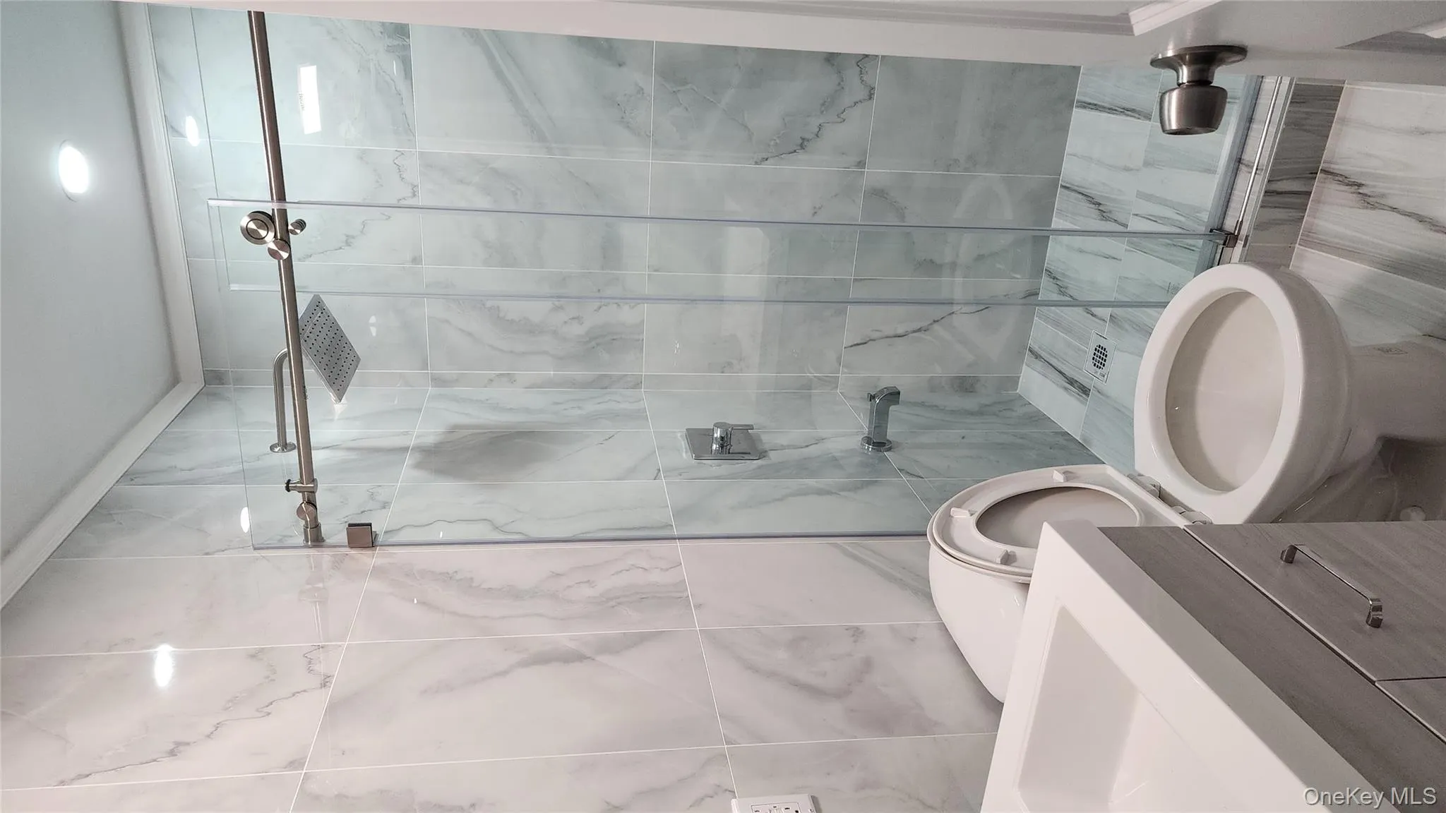 Full bathroom featuring tile walls, a marble finish shower, and vanity Full bathroom featuring tile walls, a marble finish shower, and vanity