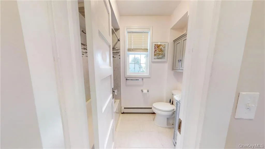 Bathroom with a baseboard heating unit, light tile patterned floors, bathtub / shower combination, and vanity Bathroom with a baseboard heating unit, light tile patterned floors, bathtub / shower combination, and vanity