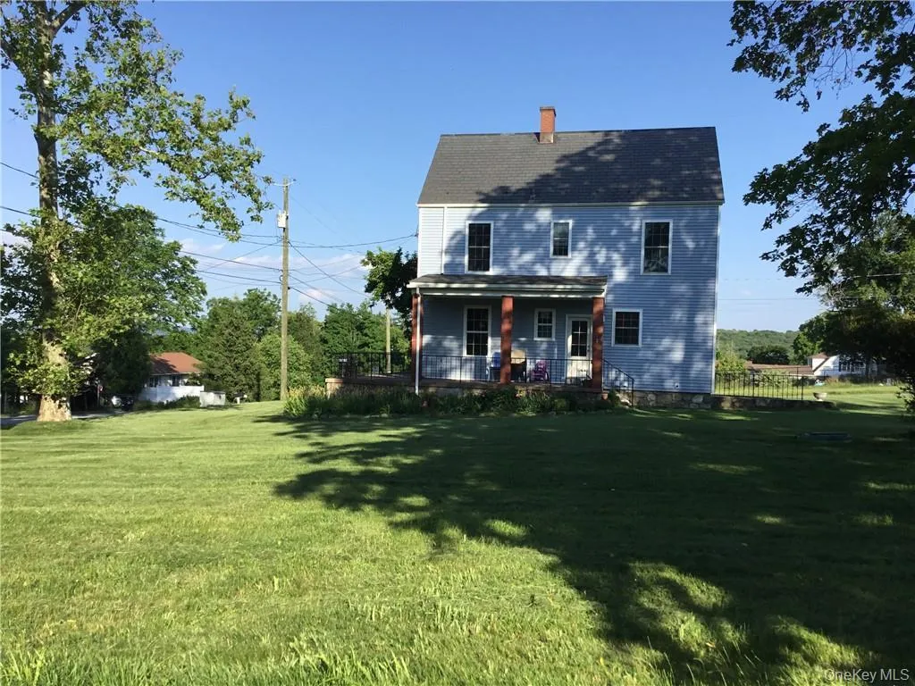 Rear view of property featuring a lawn, covered porch, and a chimney Rear view of property featuring a lawn, covered porch, and a chimney