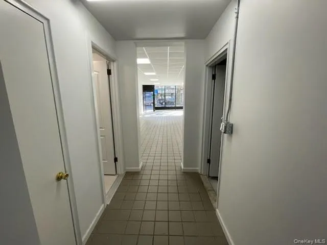Hallway with dark tile patterned floors and baseboards Hallway with dark tile patterned floors and baseboards