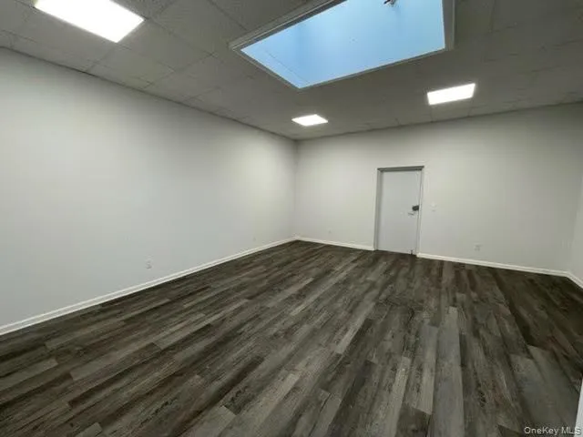 Unfurnished room featuring dark wood-style flooring and a paneled ceiling Unfurnished room featuring dark wood-style flooring and a paneled ceiling