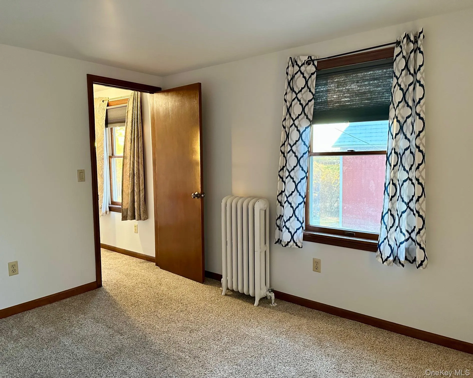 Empty room featuring radiator heating unit and carpet Empty room featuring radiator heating unit and carpet